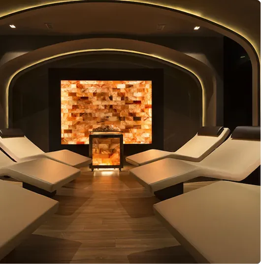 Interior moderno di una sala relax con sedie reclinabili e muro illuminato con luci calde.