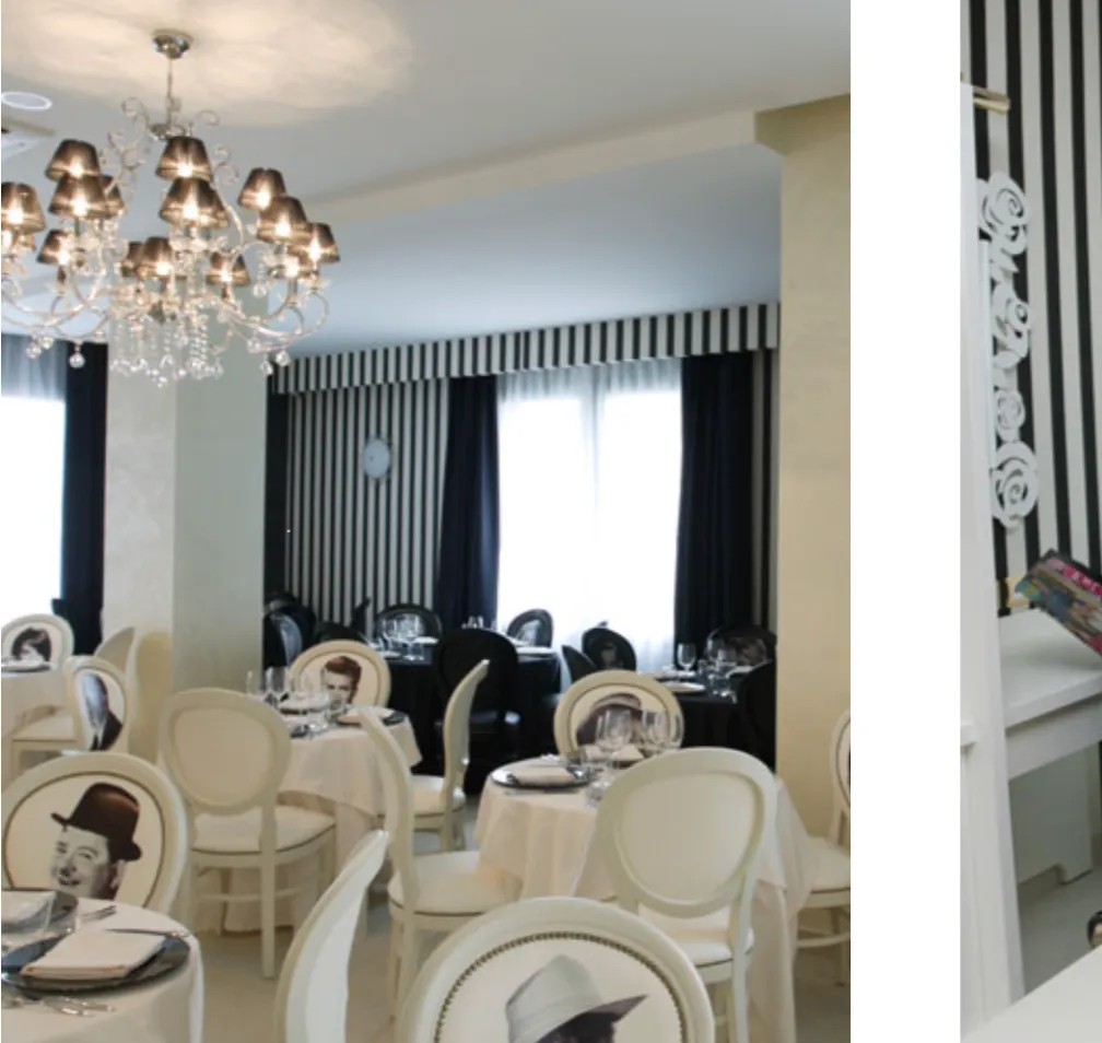 Interno di un ristorante elegante con sedie bianche e nere, alcune con immagini di volti famosi stampate sullo schienale, tovaglie bianche e grandi finestre con tende a strisce.