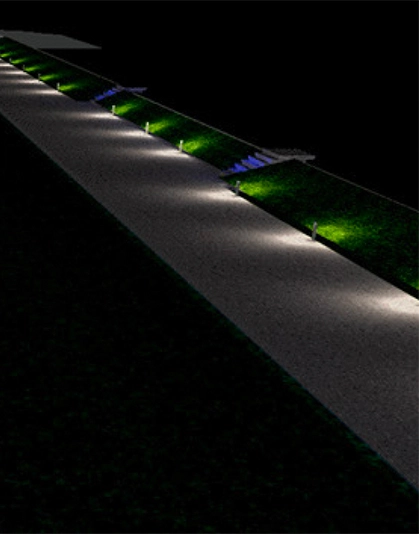 Sentiero illuminato di notte con luci da terra e aiuole verdi.