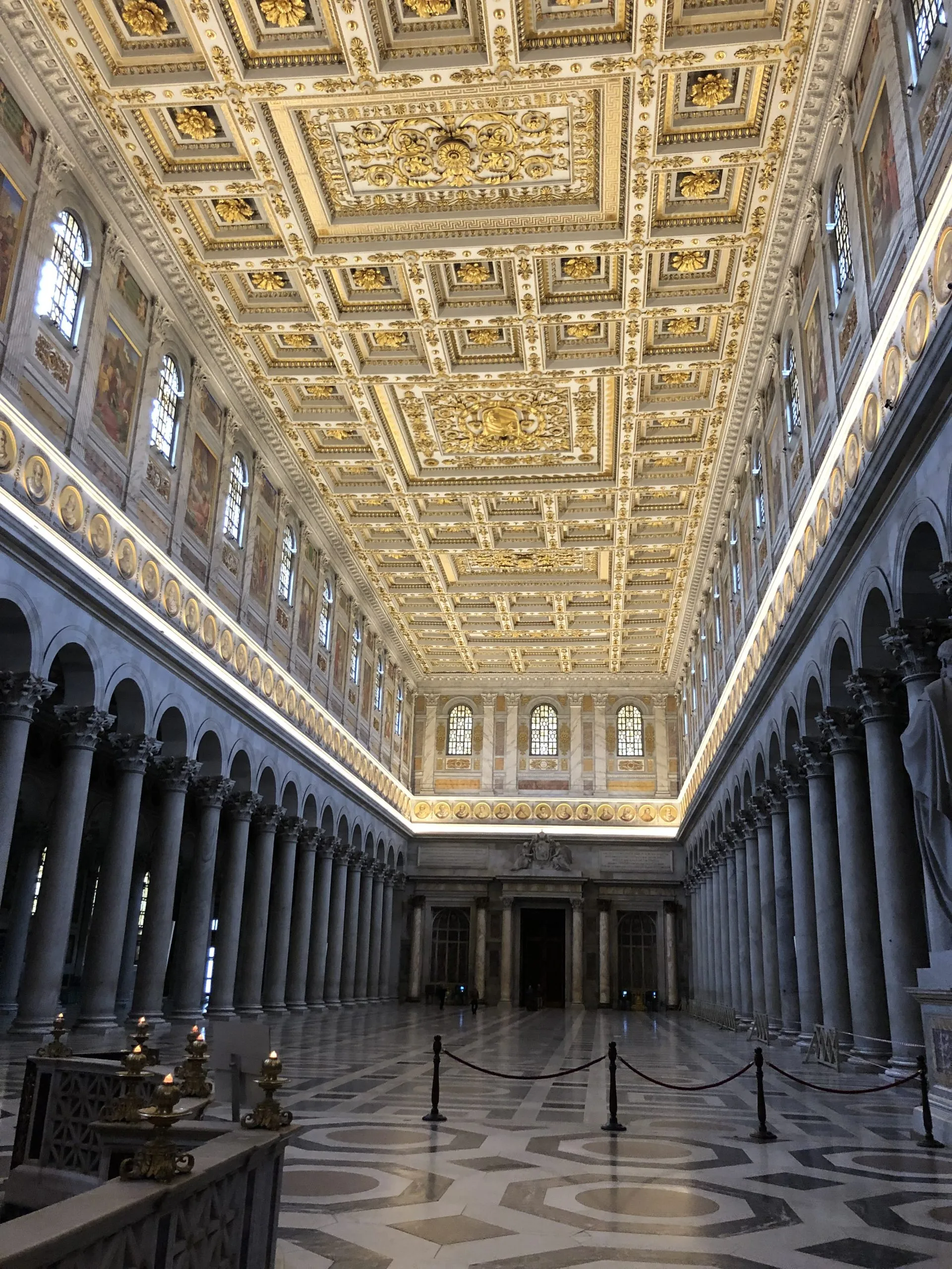 Vista dal basso verso l'alto di un edificio moderno con ampie finestre illuminate da luci arancioni, blu e viola di sera.