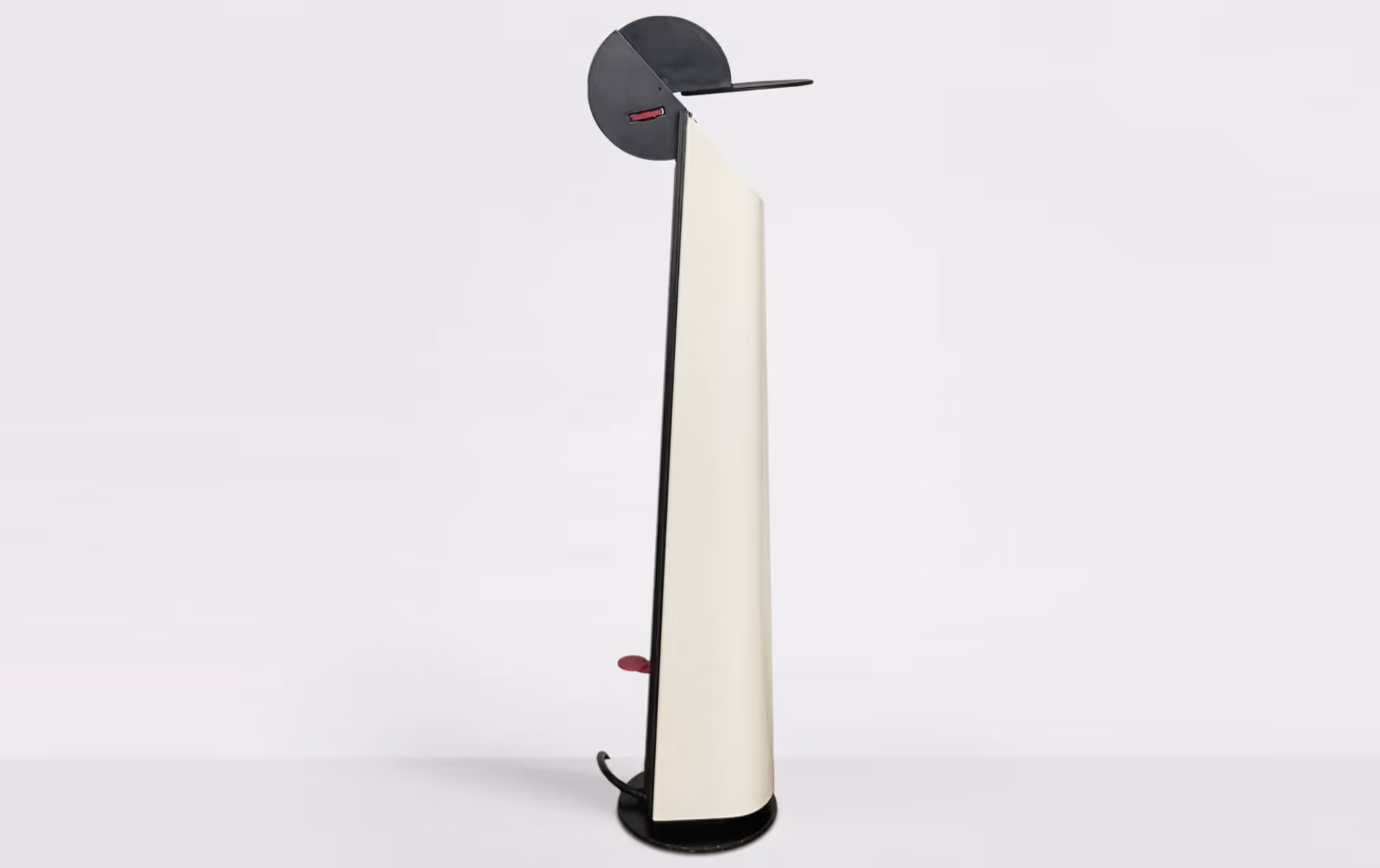 Lampada da terra moderna con base nera rotonda e paralume bianco a forma trapezoidale con elemento circolare nero sopra.