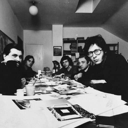 Due uomini in giacca e cravatta esaminano un grande globo luminoso sopra un cilindro nero su una scrivania.