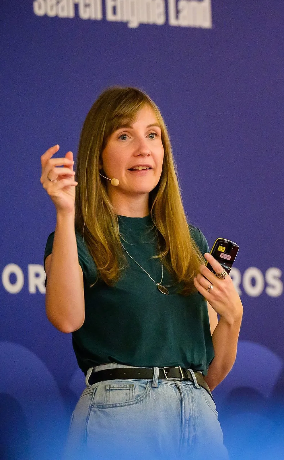 Viola speaking at a conference. She is wearing a white shirt. The background is dark