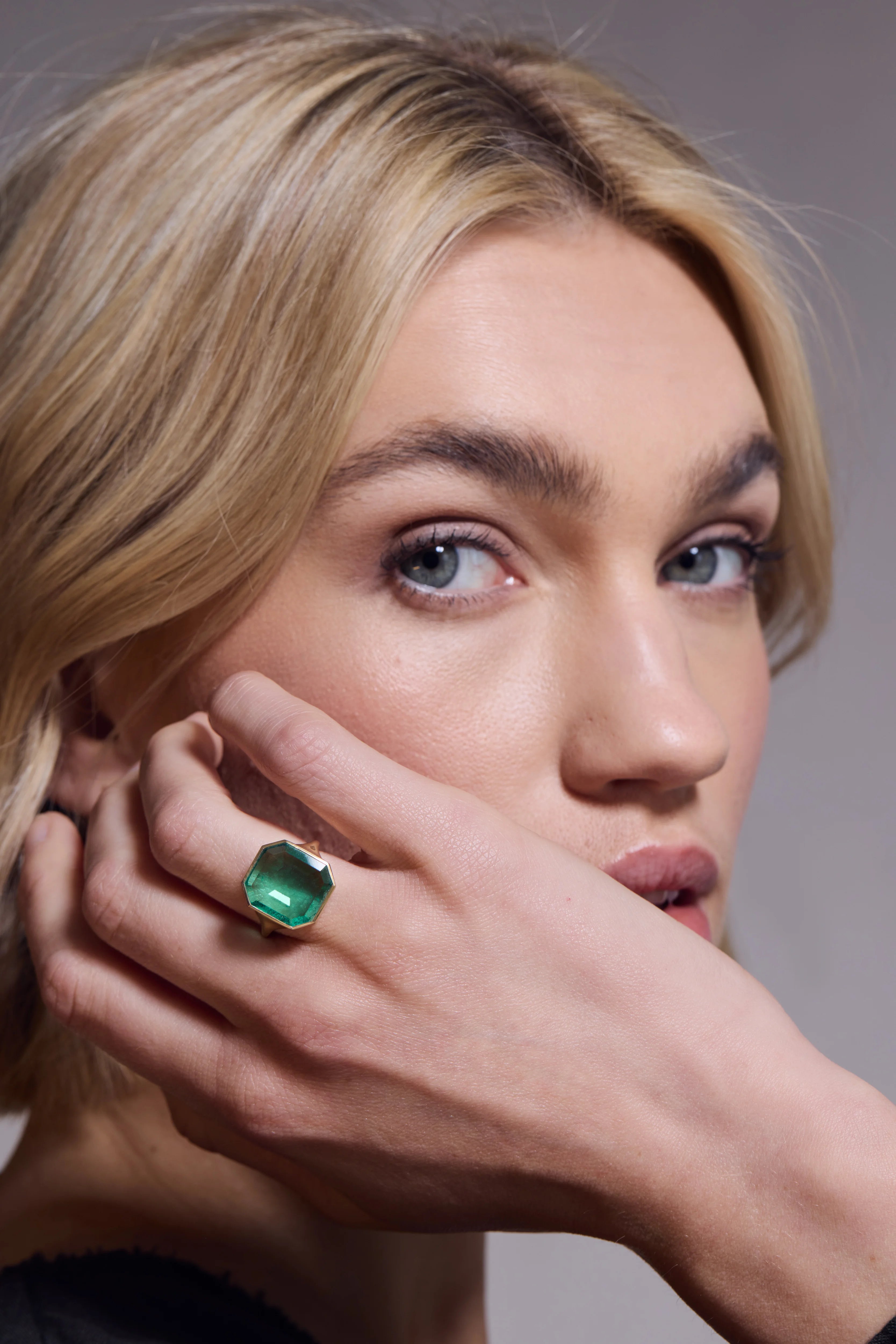 Woman wearing a green gemstone ring on her finger.