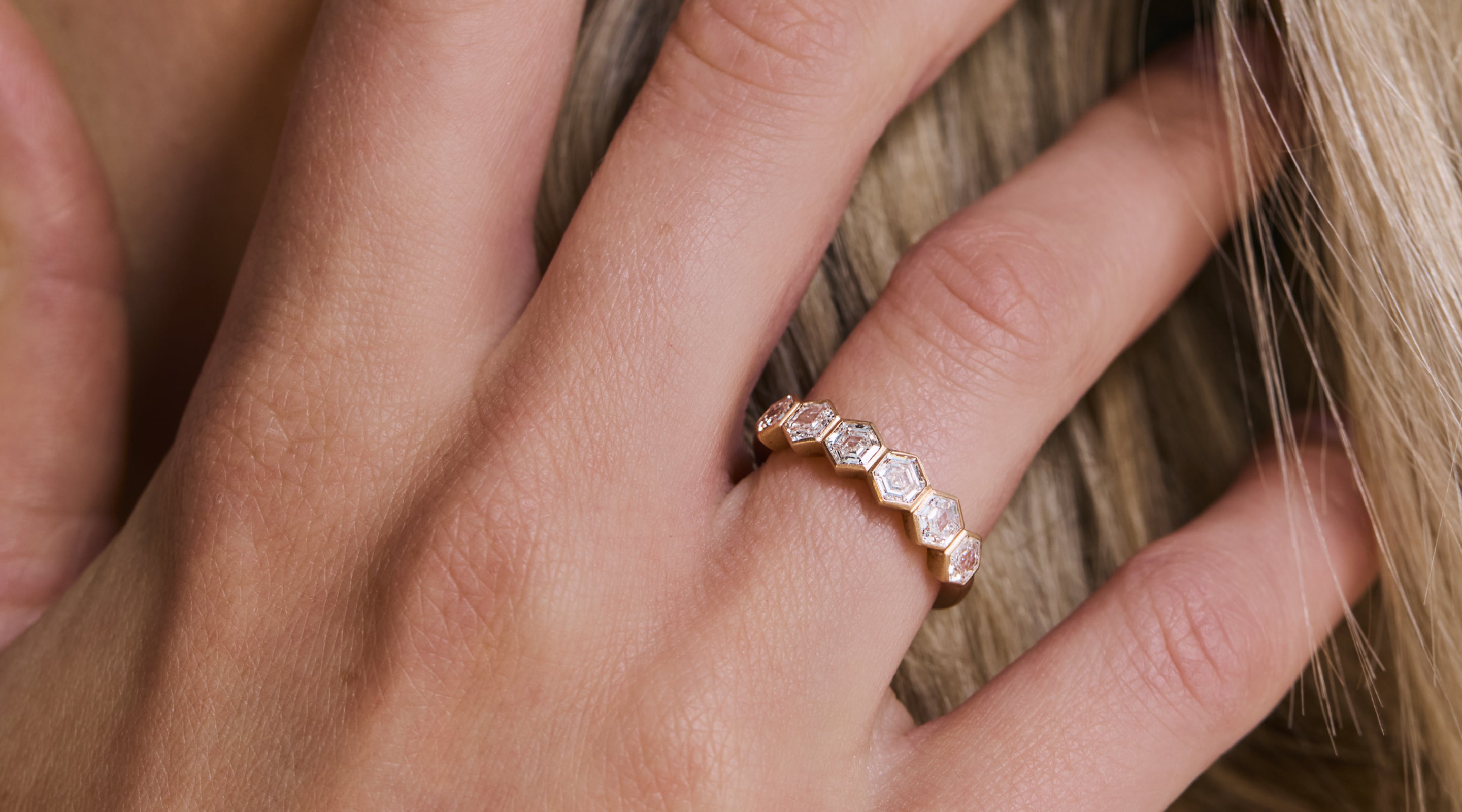 Blonde woman with slicked-back hair wearing a black strapless top and a choker necklace with a large light blue gemstone.