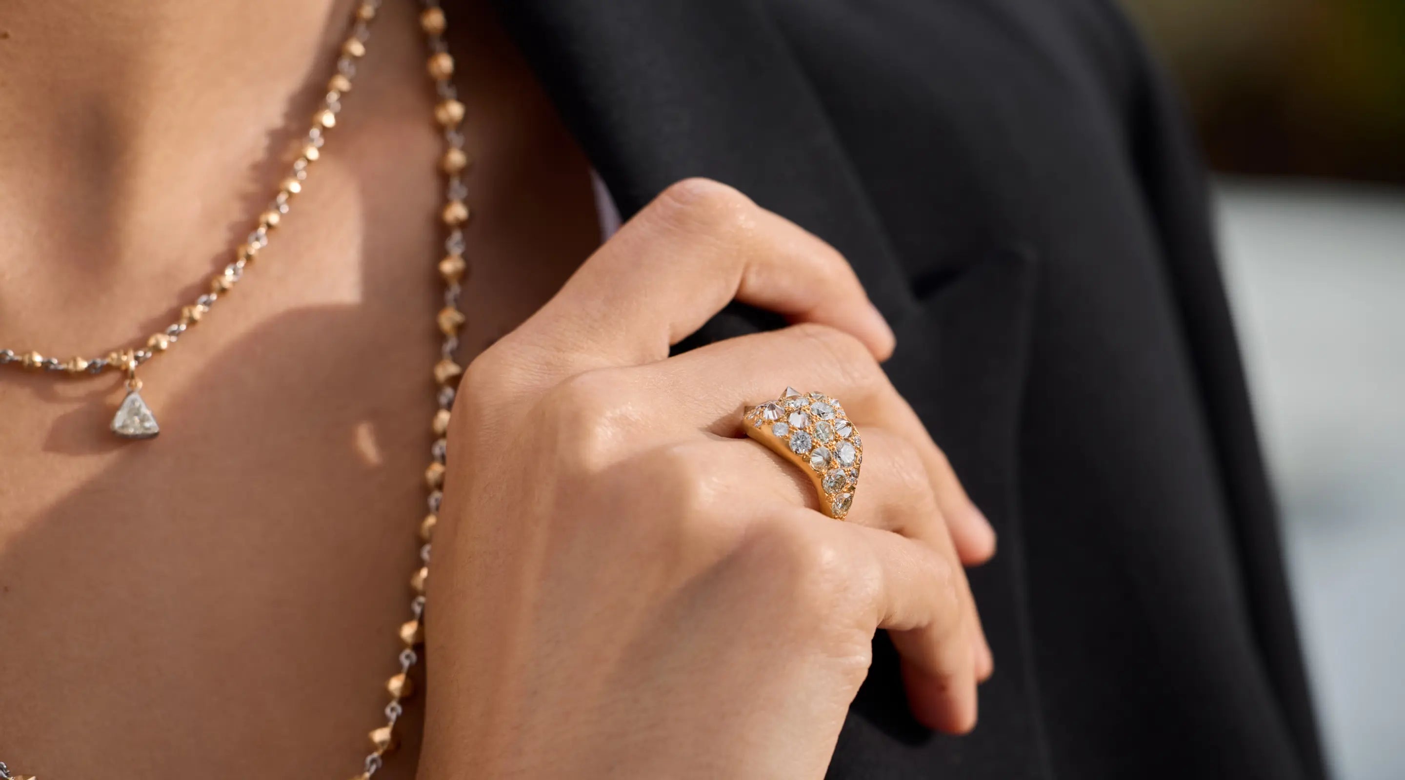 Blonde woman with slicked-back hair wearing a black strapless top and a choker necklace with a large light blue gemstone.