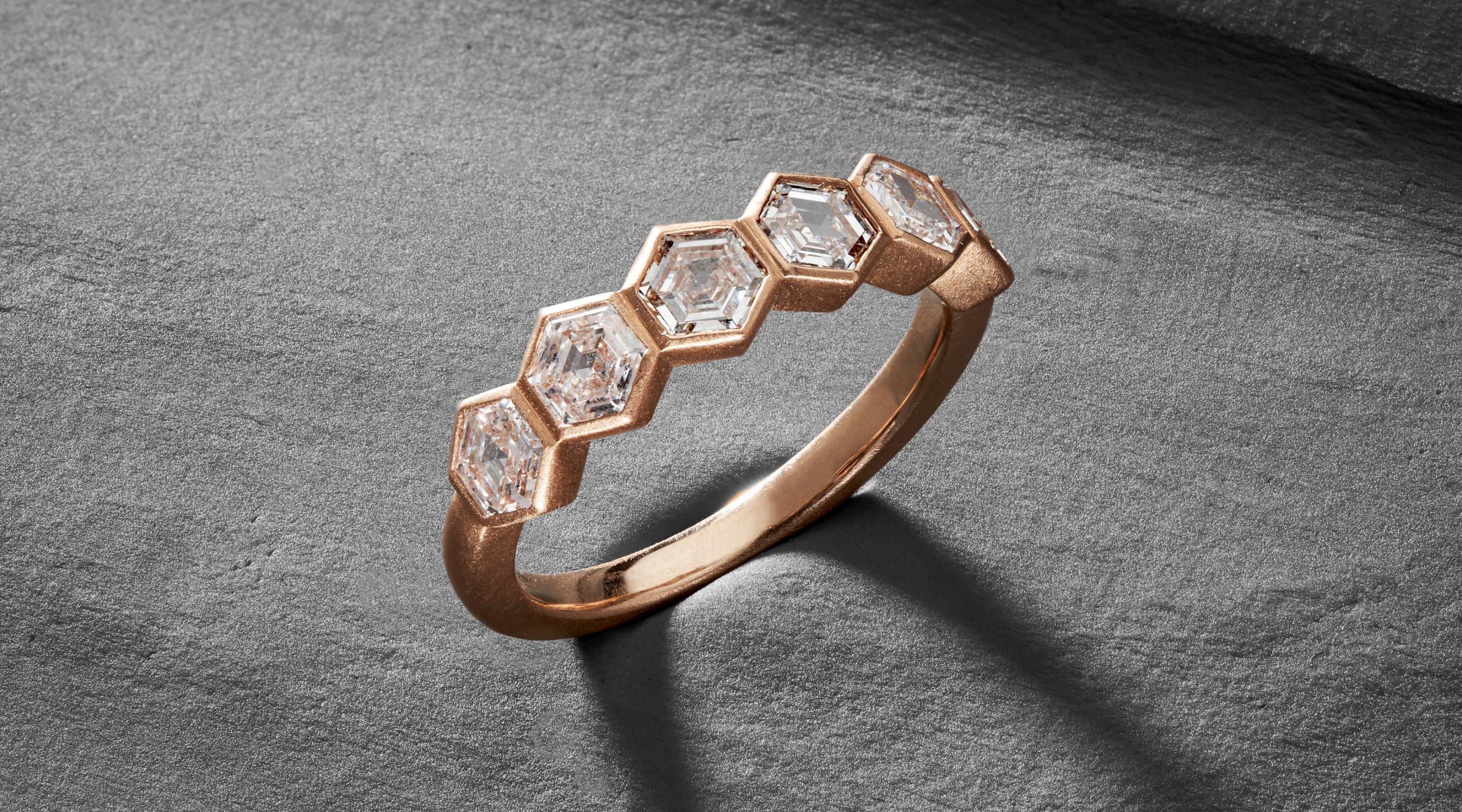 Blonde woman with slicked-back hair wearing a black strapless top and a choker necklace with a large light blue gemstone.