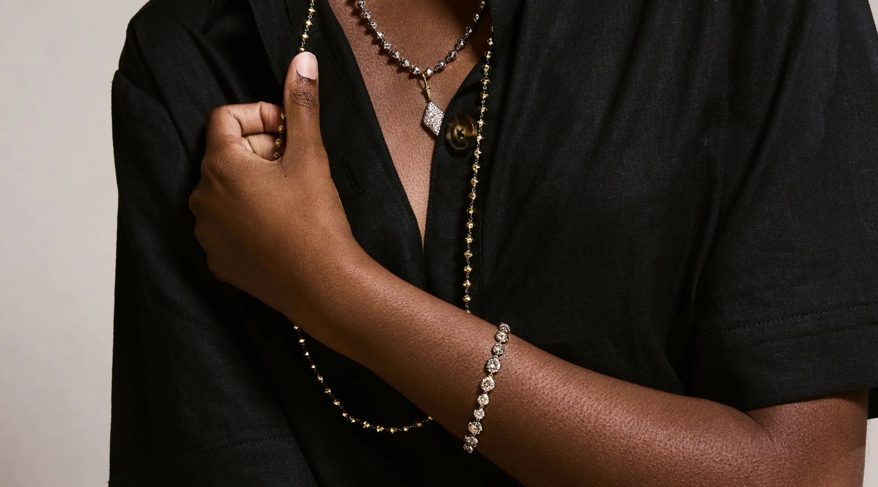 Blonde woman with slicked-back hair wearing a black strapless top and a choker necklace with a large light blue gemstone.