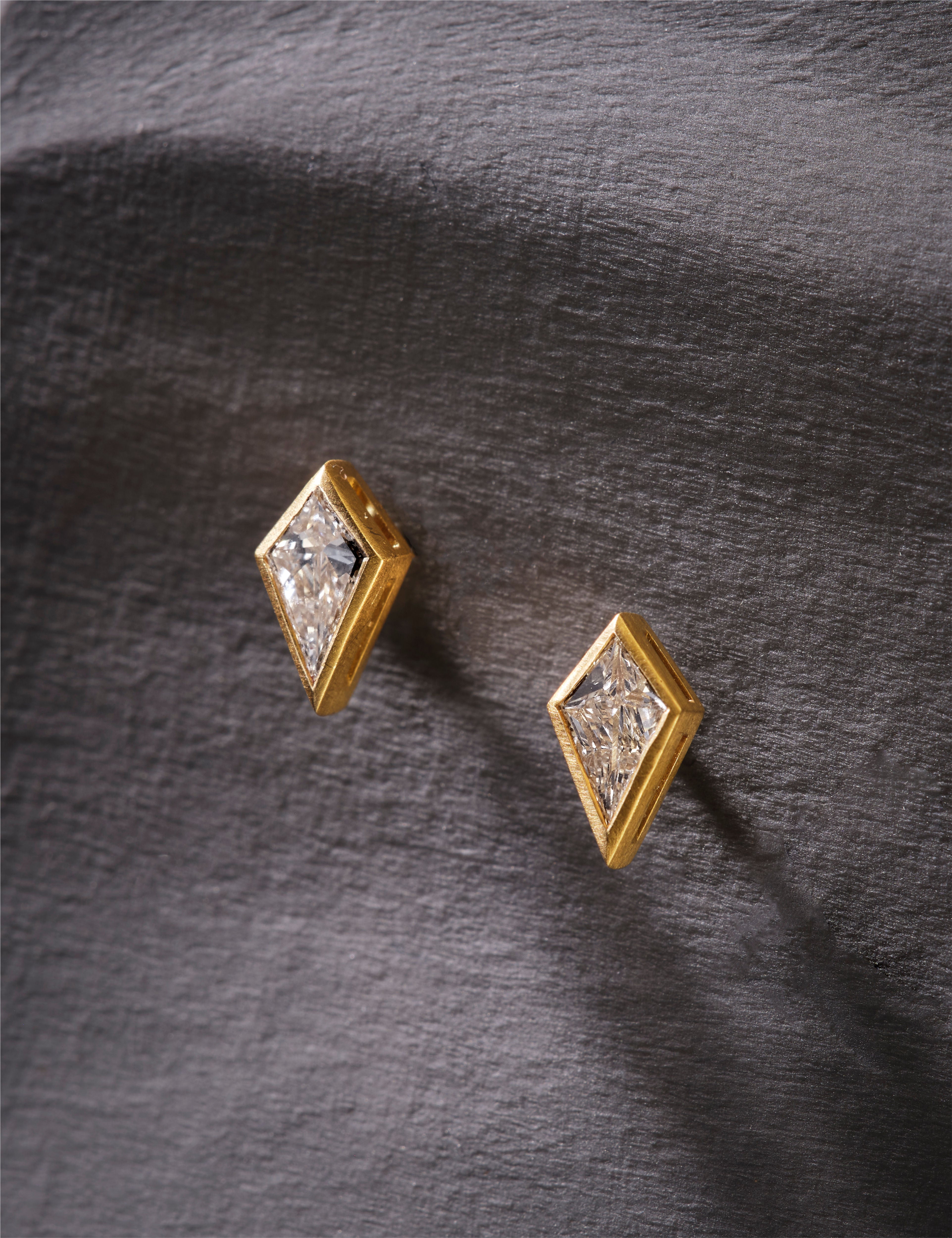 Gold stud earrings with clear gemstones on a white background.