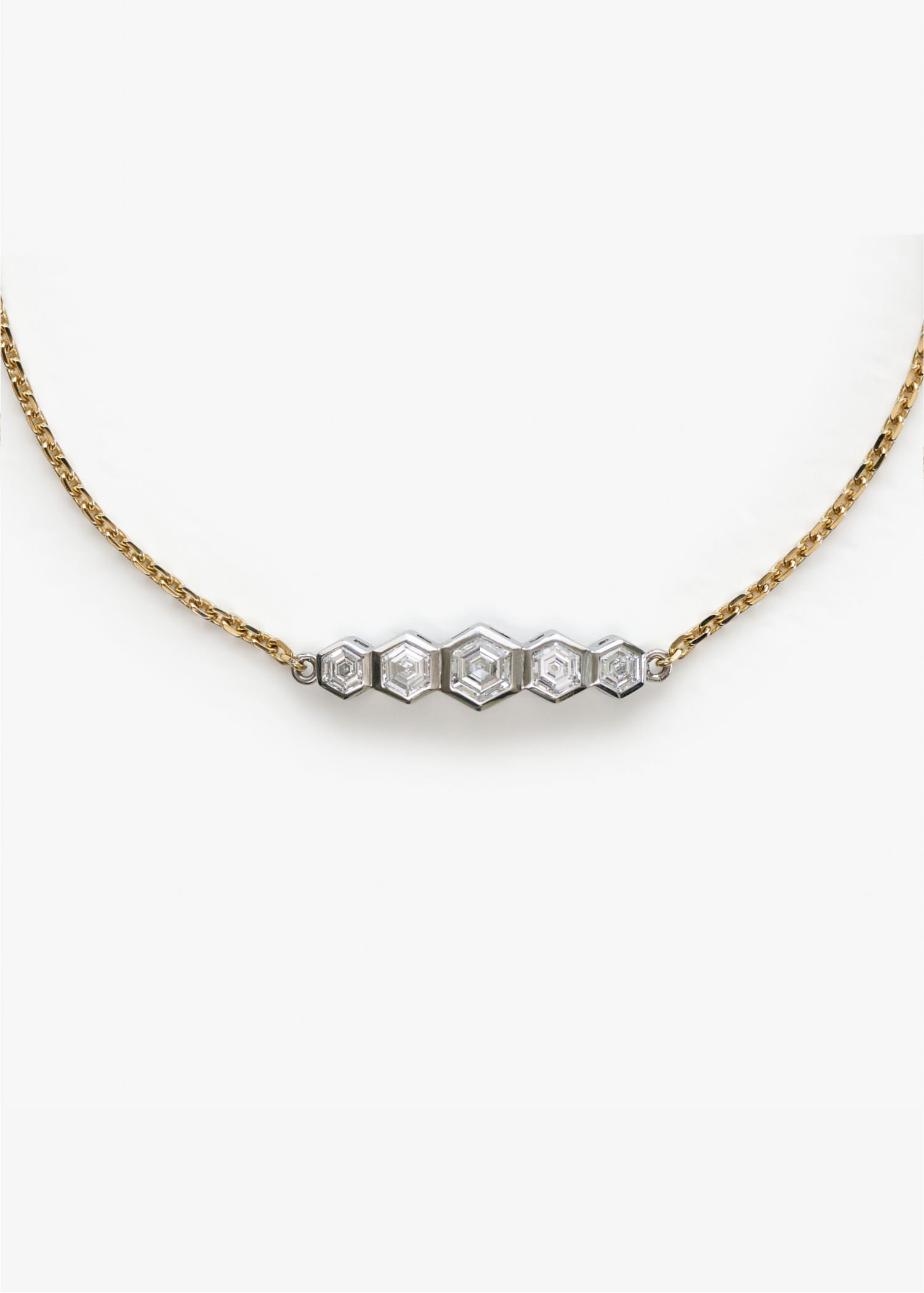 Detailed view of yellow gold bracelet showcasing five hexagon-cut diamonds in white gold settings.