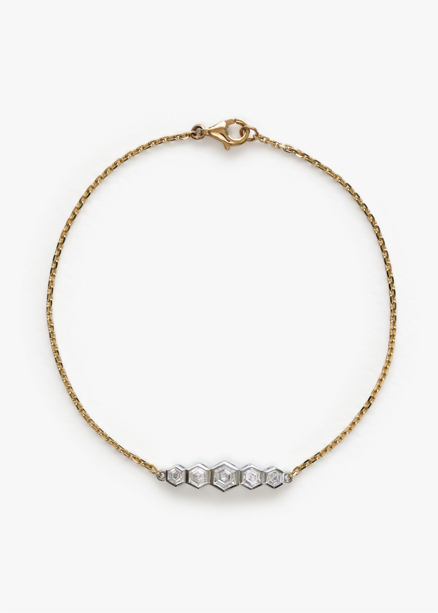 Yellow gold bracelet featuring five hexagon-cut diamonds set in geometric white gold pattern on grey background.