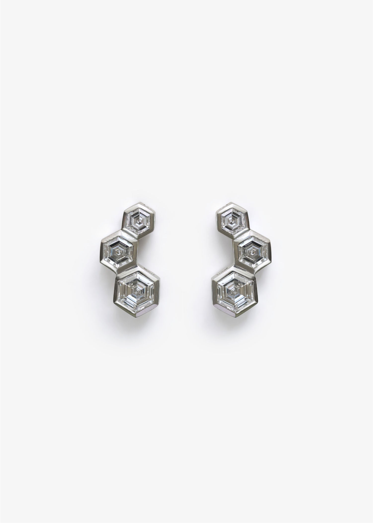 Pair of silver hexagonal earrings on a white background.