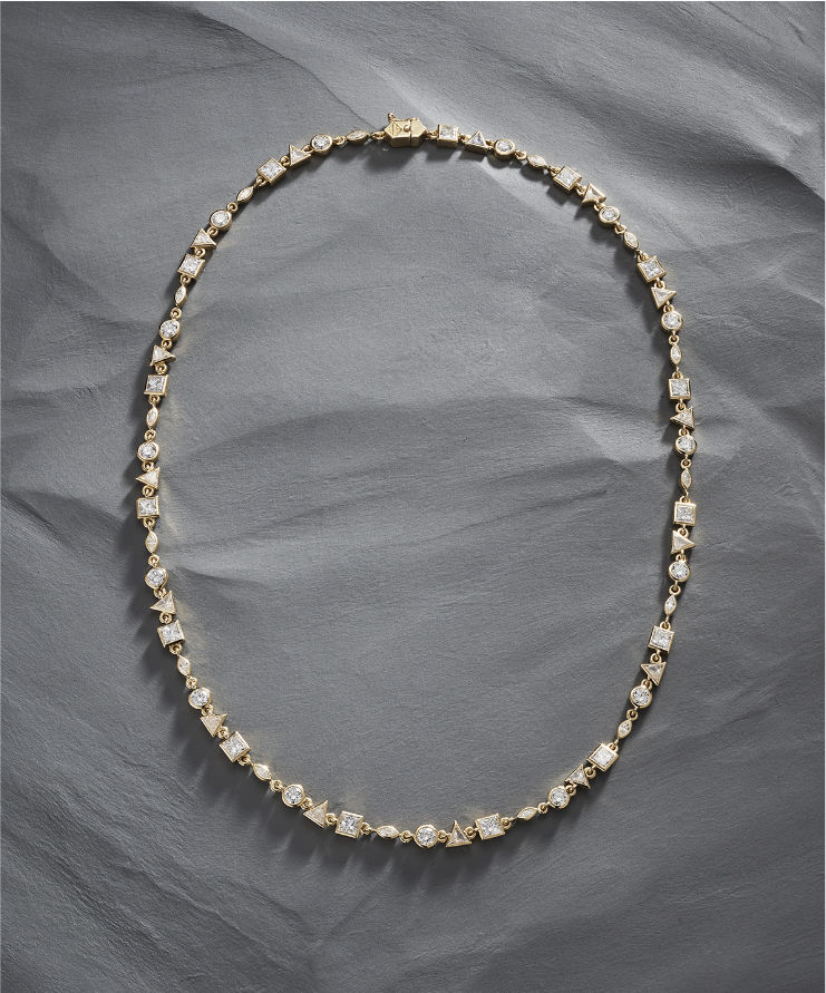 Close-up of yellow gold diamond tennis necklace showcasing geometric diamond cuts including round, square, and triangle shapes.