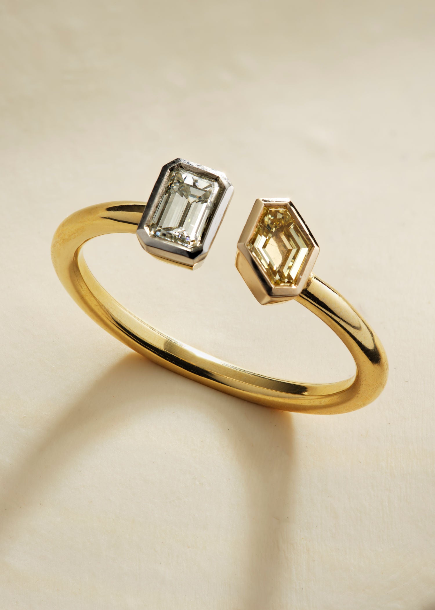 Close-up of toi et moi ring featuring white and champagne emerald-cut diamonds set in yellow gold.