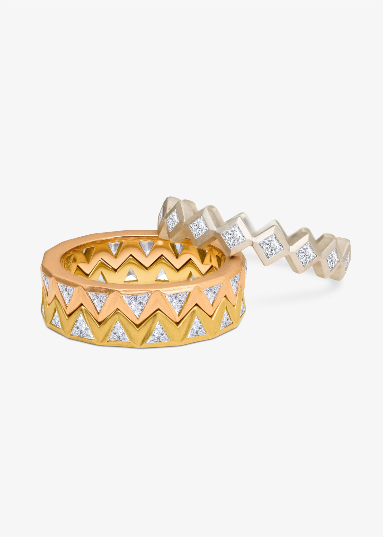 Gold ring with geometric design on a beige surface.
