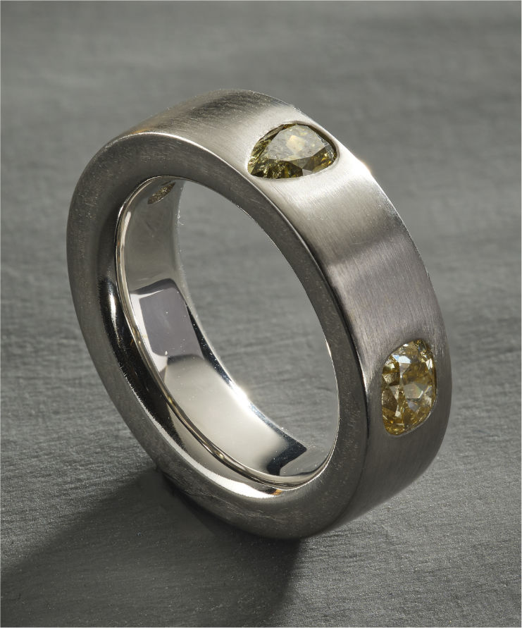 Platinum ring with yellow pear and oval-cut diamonds on brushed finish.