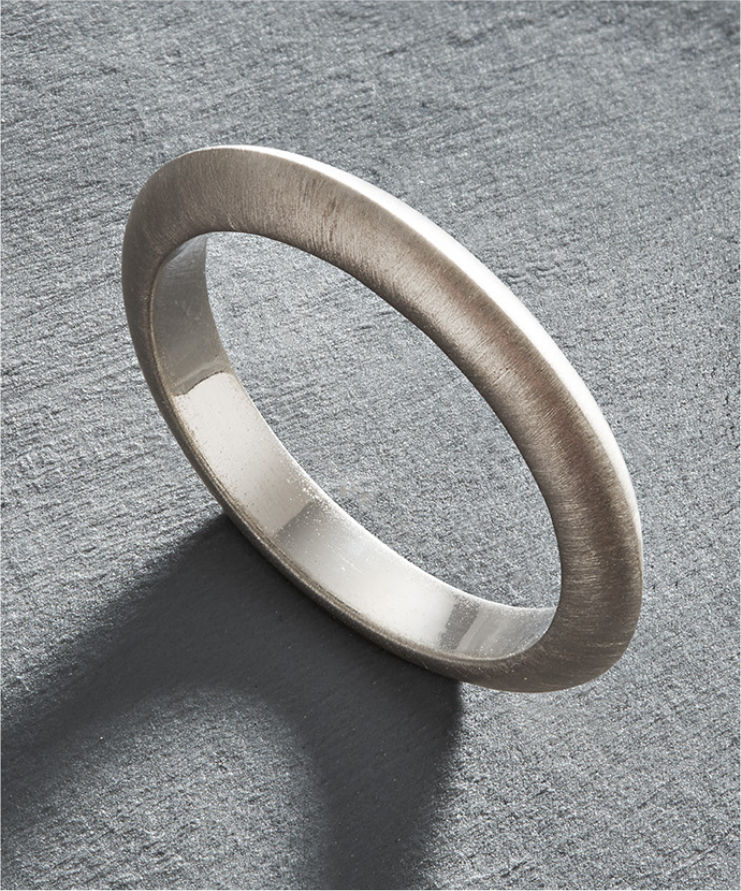 Close-up of a person wearing a brown pinstripe garment with a gold ring and bracelet.