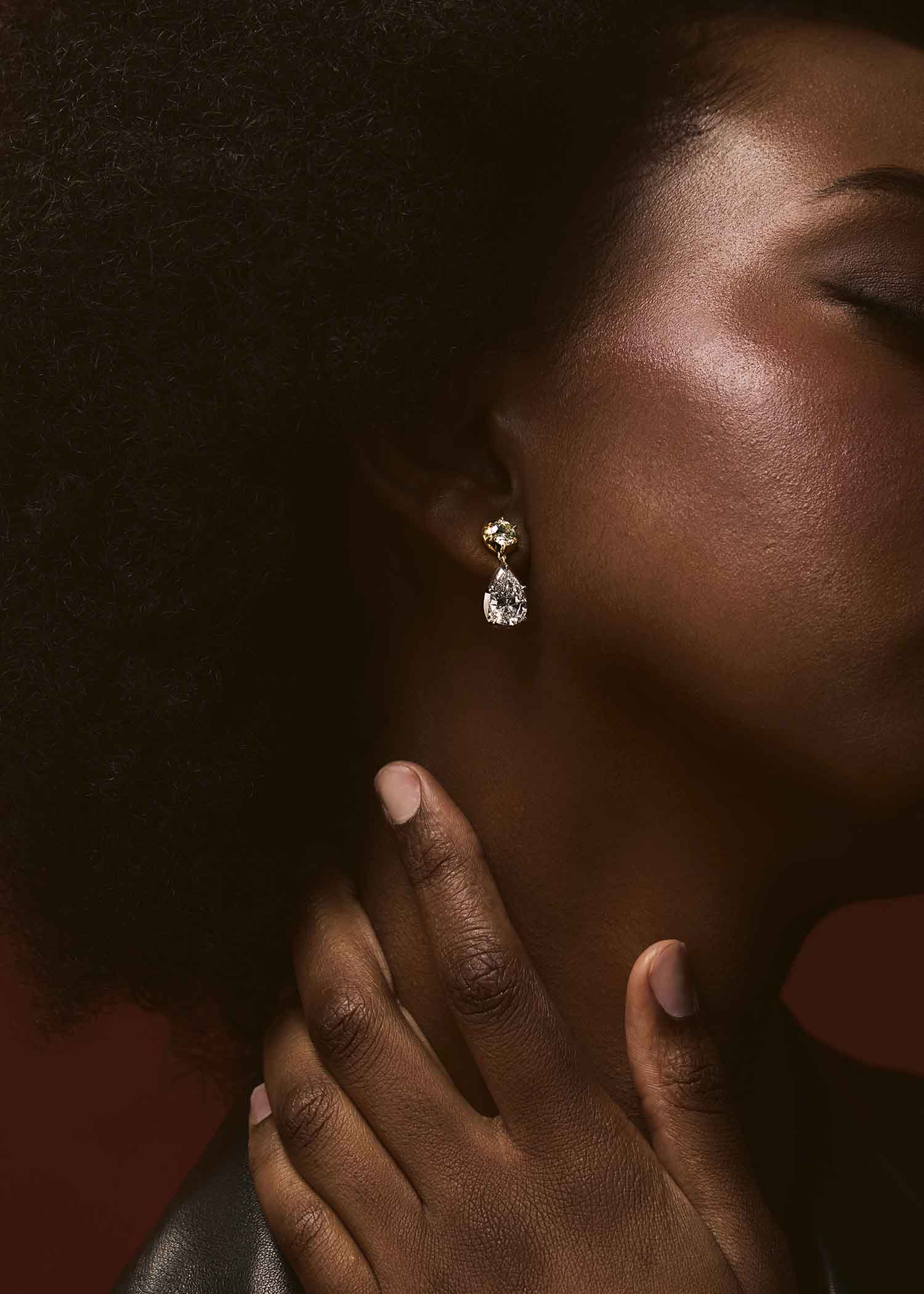 Diamond earring worn on an ear against a dark background.