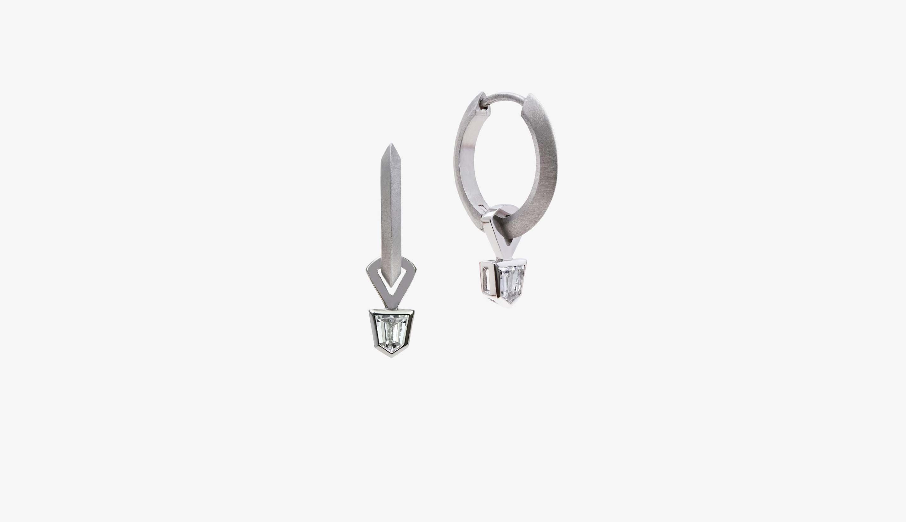 Blonde woman with slicked-back hair wearing a black strapless top and a choker necklace with a large light blue gemstone.