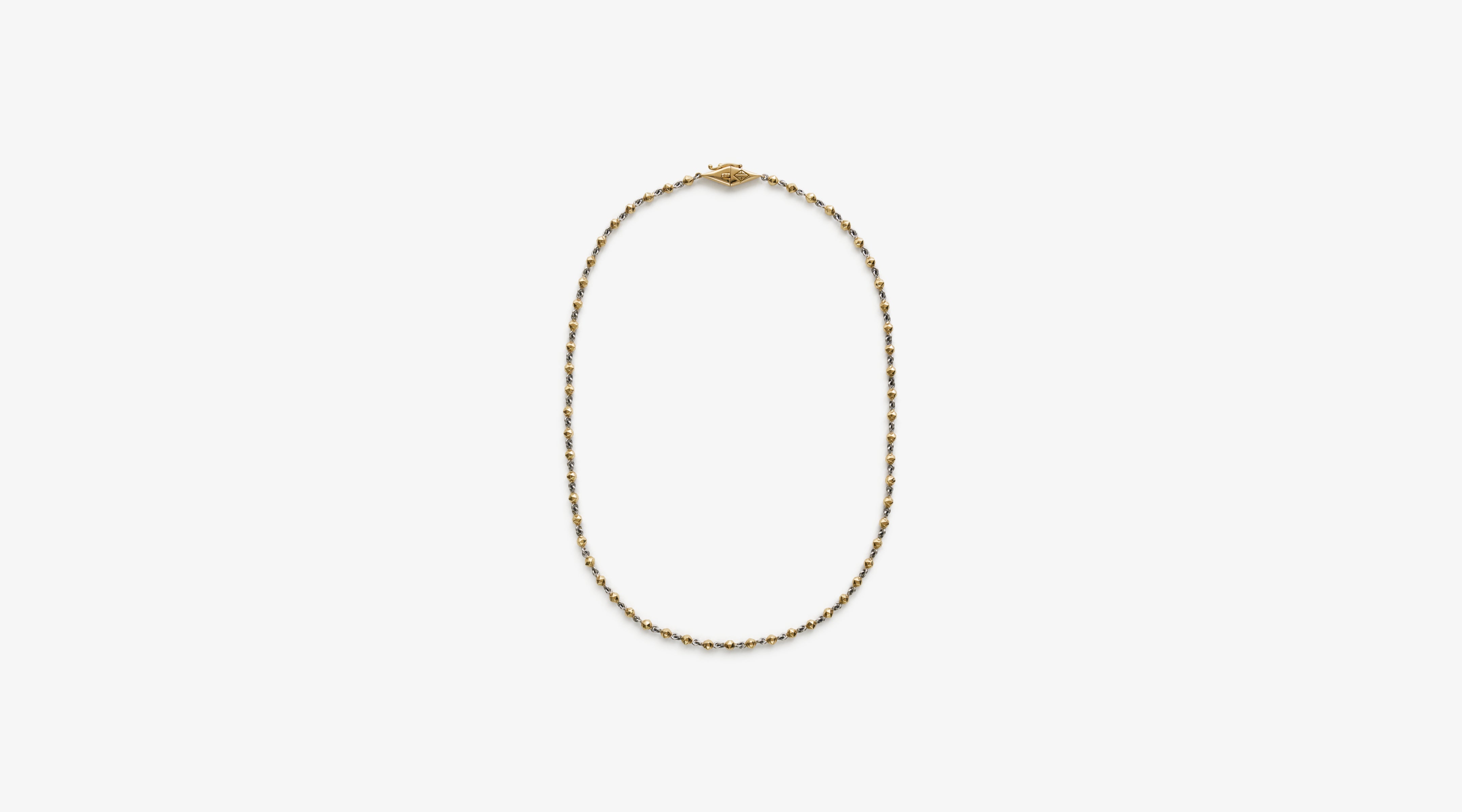 Blonde woman with slicked-back hair wearing a black strapless top and a choker necklace with a large light blue gemstone.