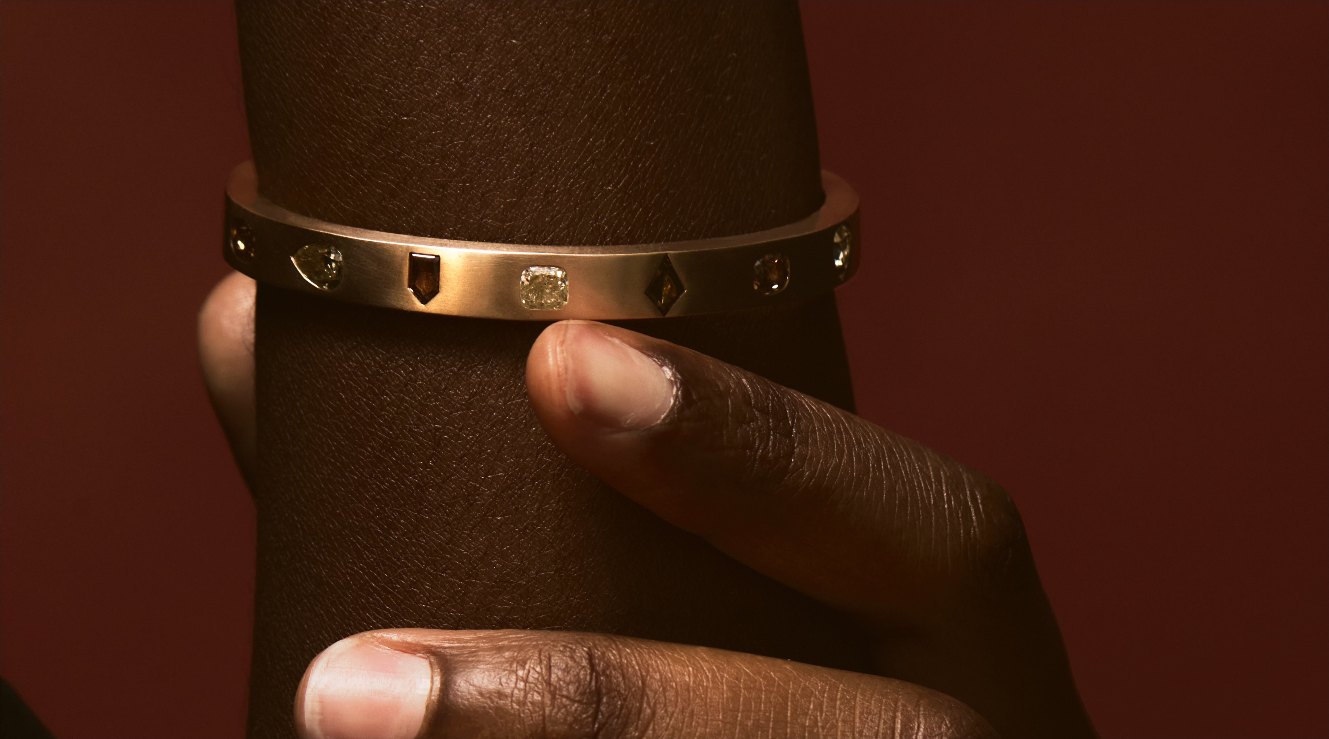 Blonde woman with slicked-back hair wearing a black strapless top and a choker necklace with a large light blue gemstone.