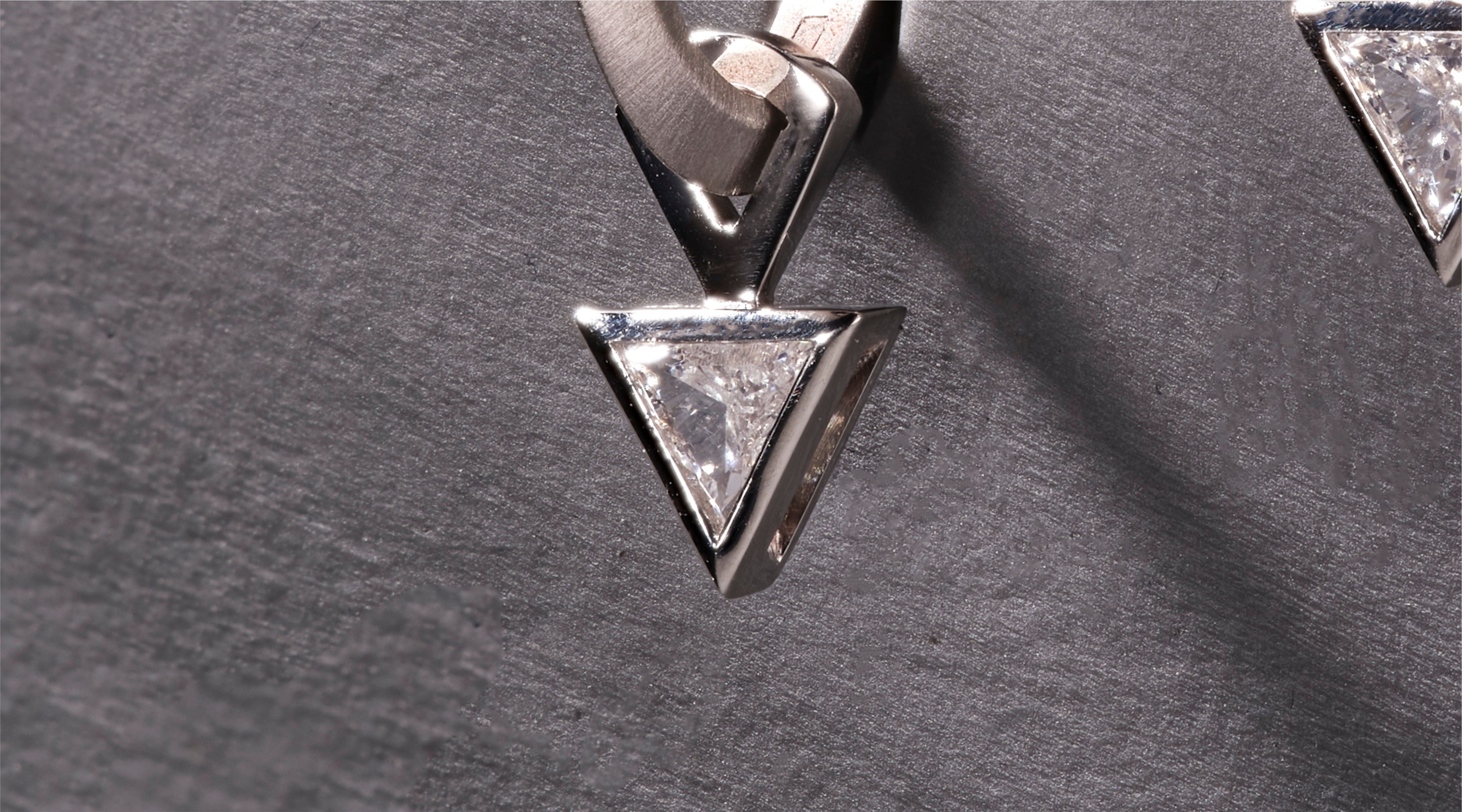 Blonde woman with slicked-back hair wearing a black strapless top and a choker necklace with a large light blue gemstone.