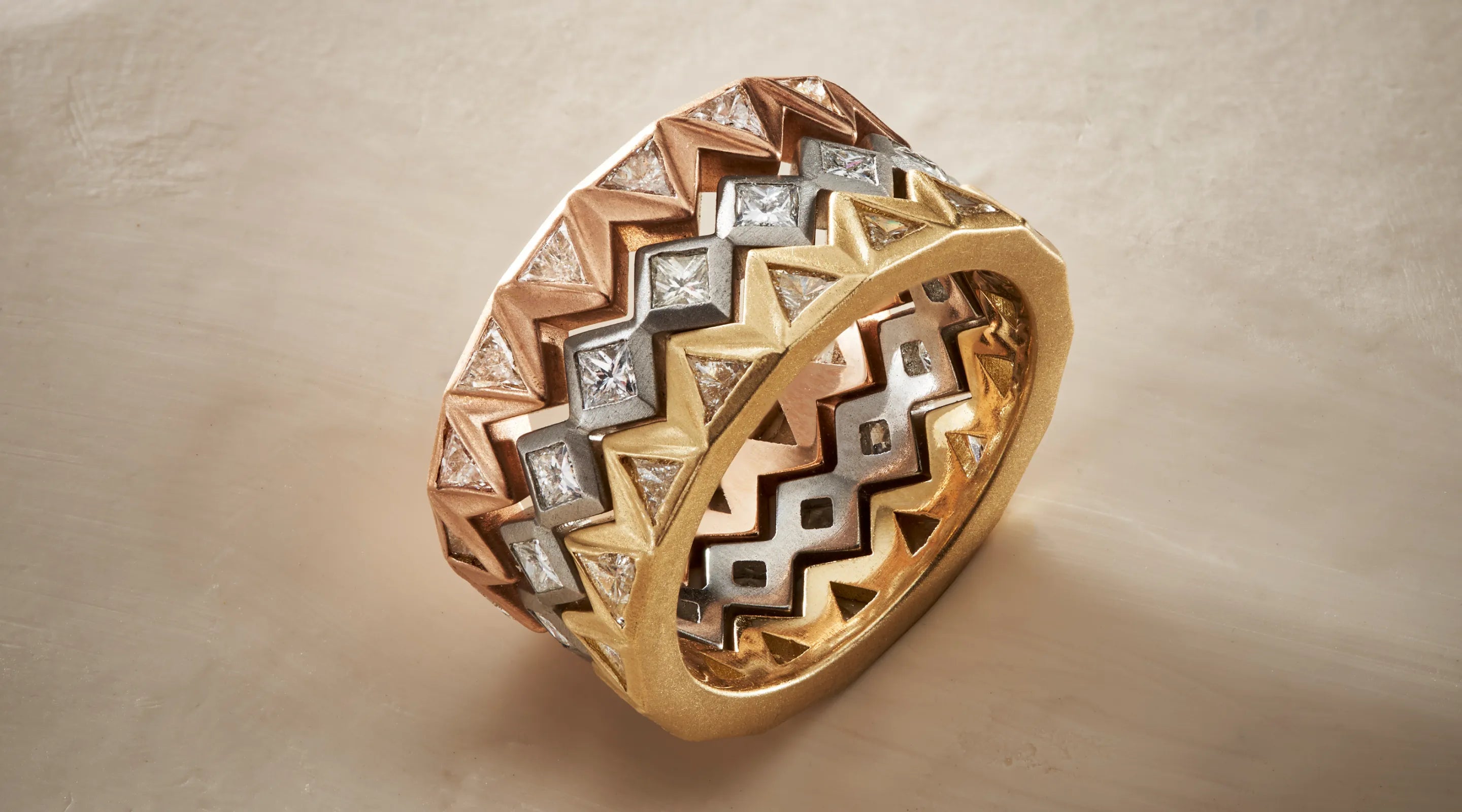 Blonde woman with slicked-back hair wearing a black strapless top and a choker necklace with a large light blue gemstone.