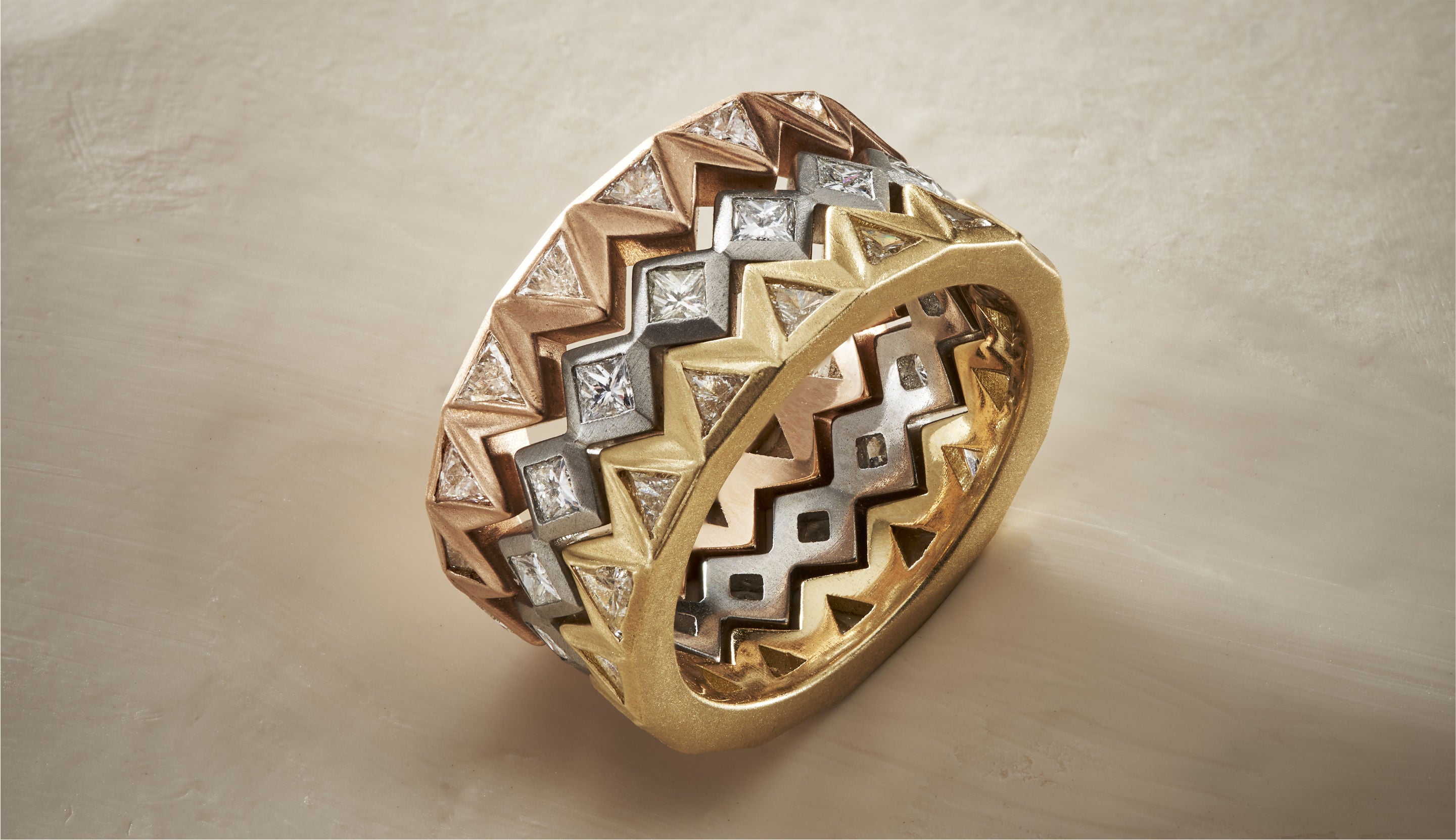 Blonde woman with slicked-back hair wearing a black strapless top and a choker necklace with a large light blue gemstone.