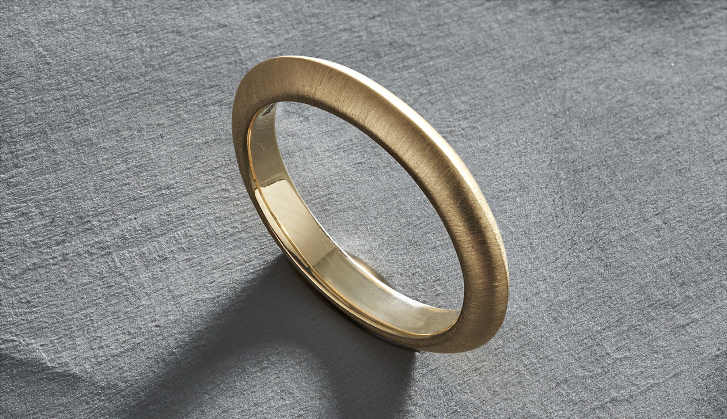 Blonde woman with slicked-back hair wearing a black strapless top and a choker necklace with a large light blue gemstone.