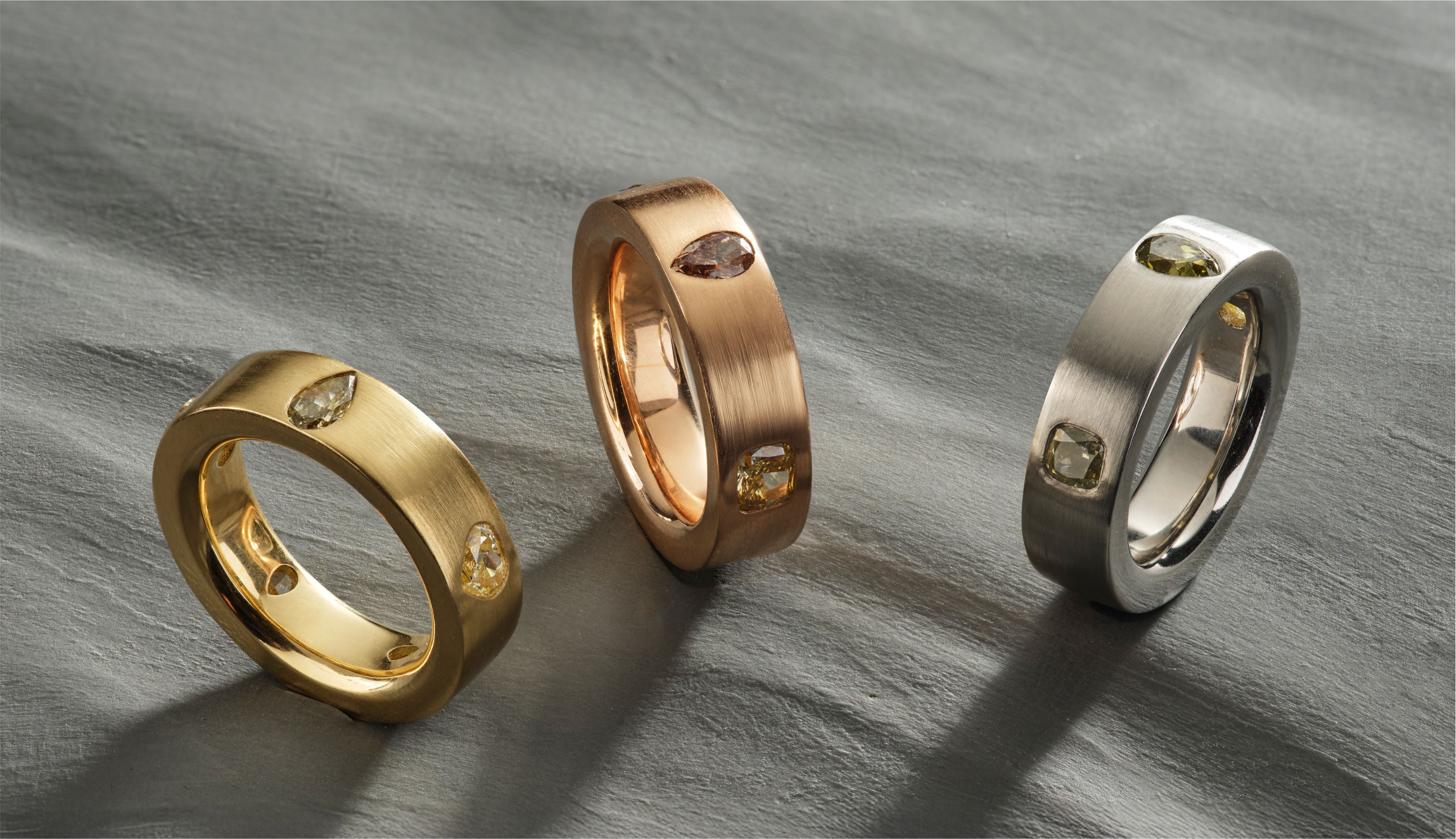 Blonde woman with slicked-back hair wearing a black strapless top and a choker necklace with a large light blue gemstone.