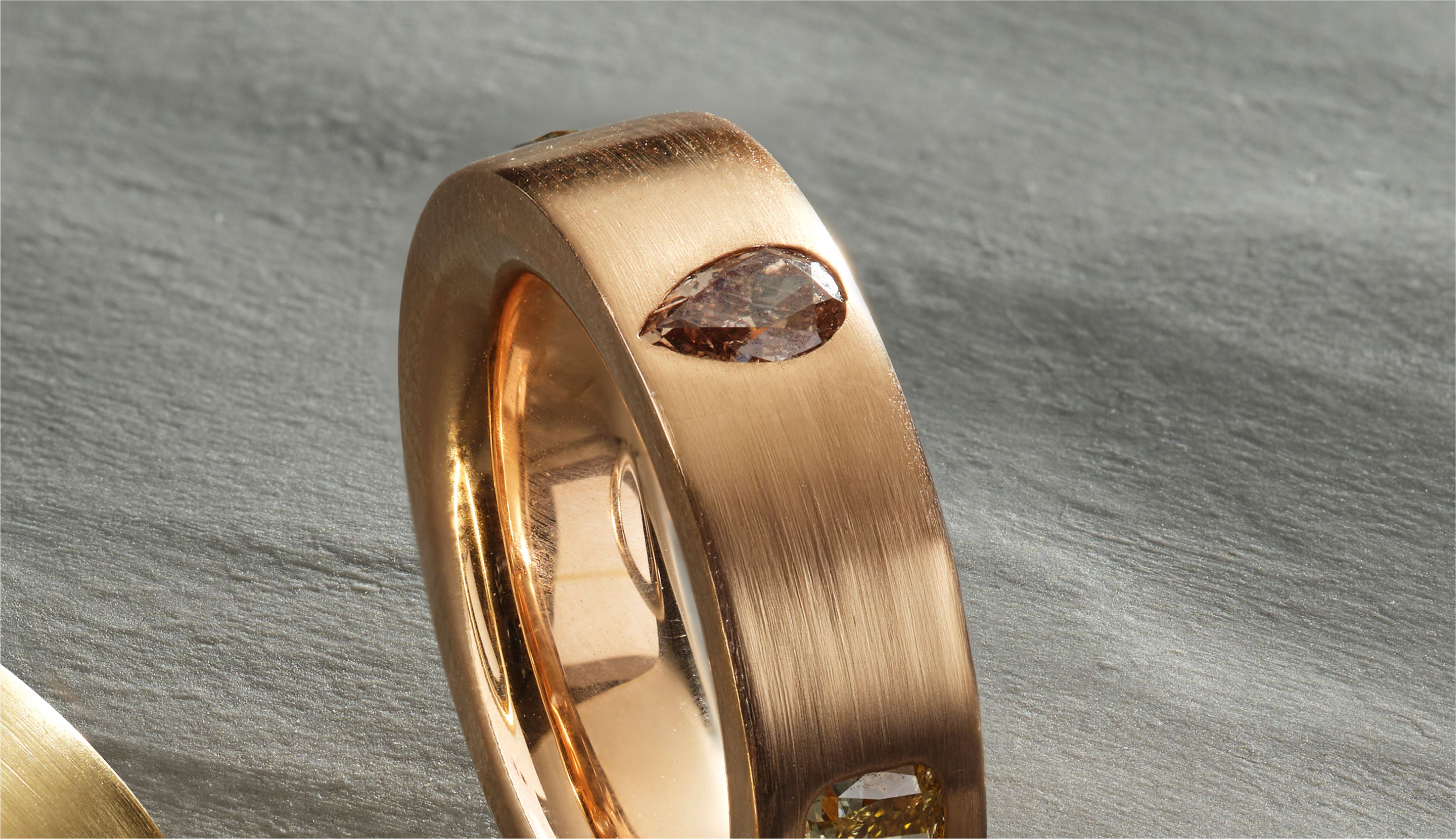 Blonde woman with slicked-back hair wearing a black strapless top and a choker necklace with a large light blue gemstone.