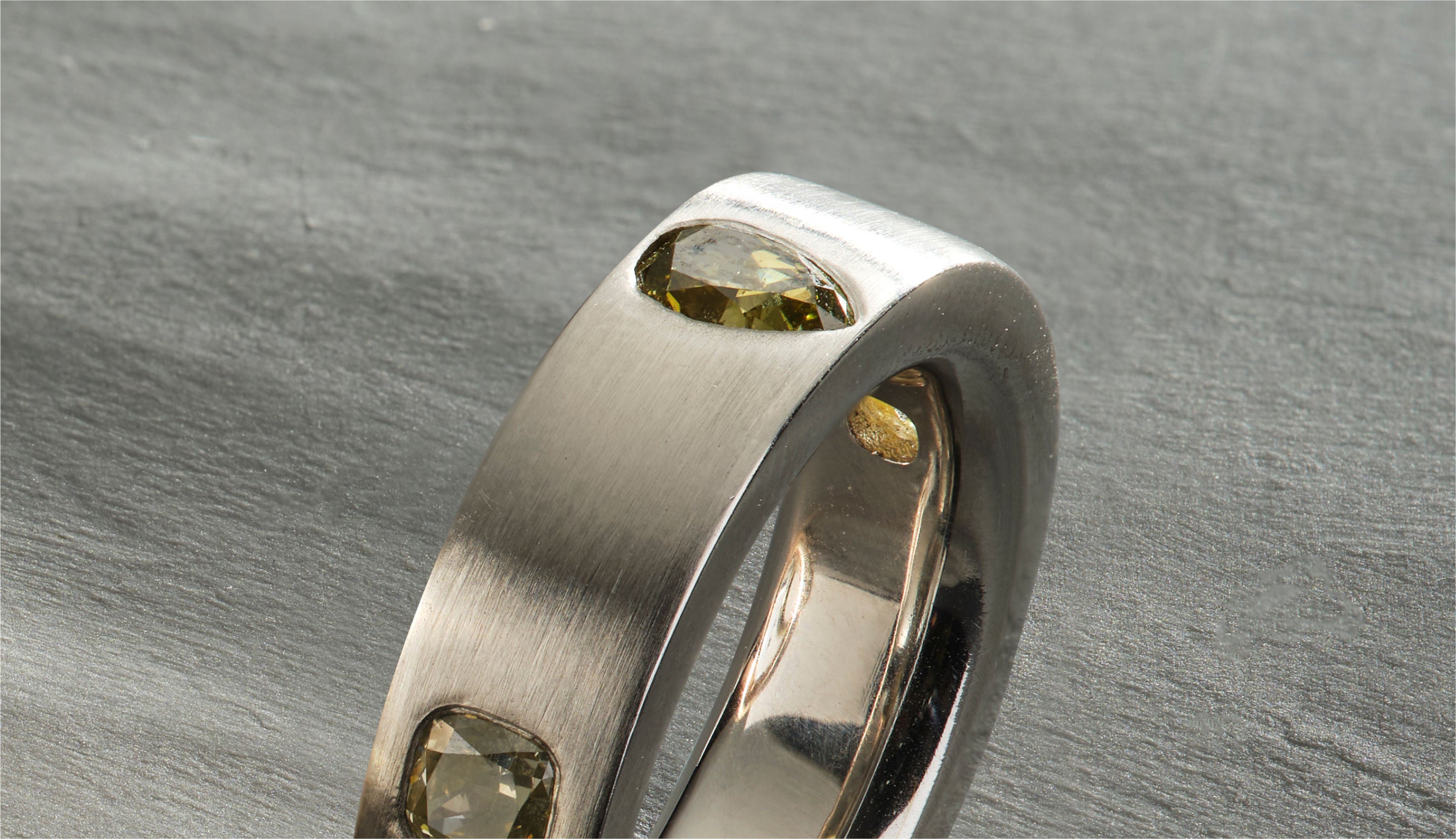 Blonde woman with slicked-back hair wearing a black strapless top and a choker necklace with a large light blue gemstone.