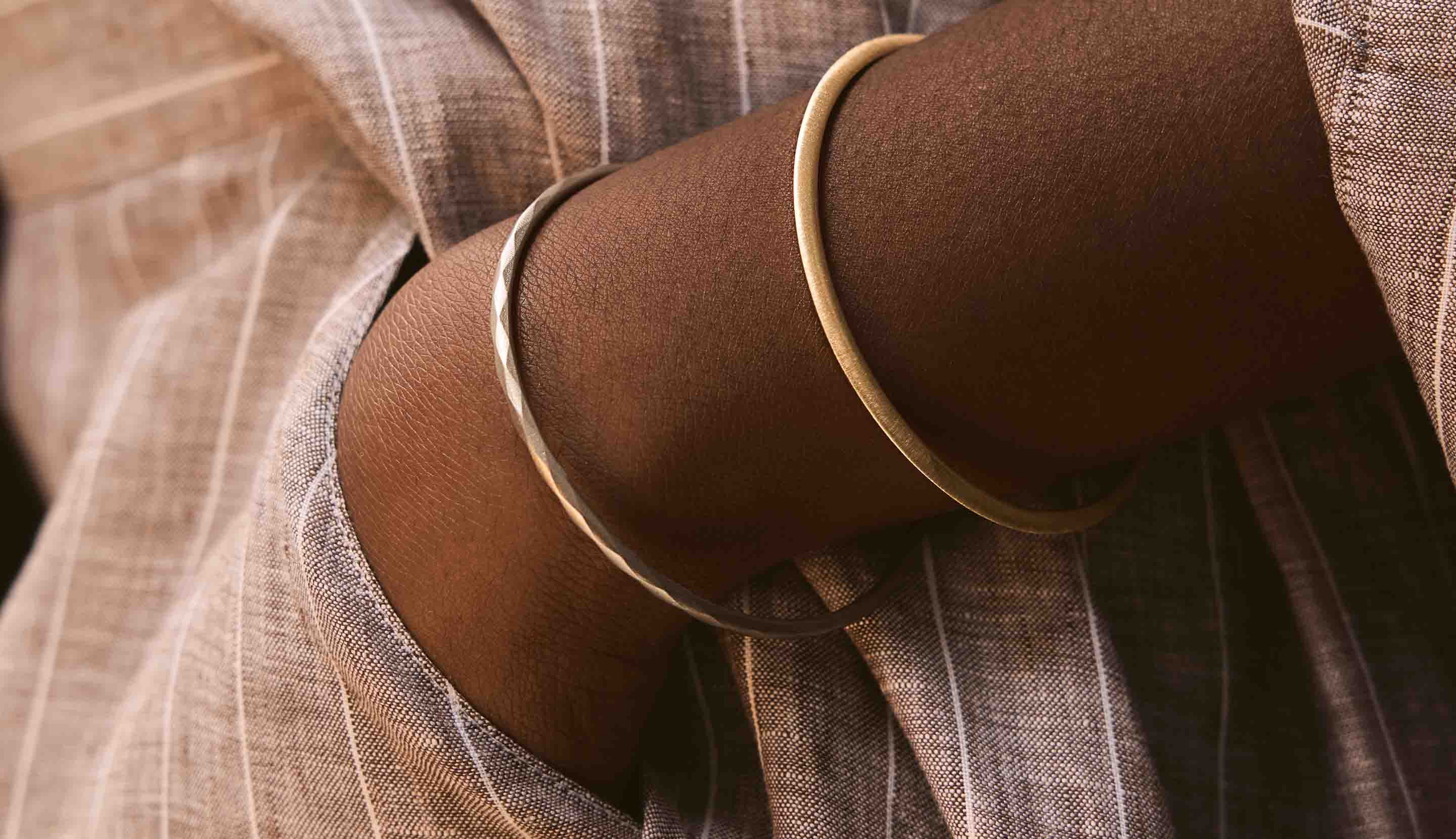 Blonde woman with slicked-back hair wearing a black strapless top and a choker necklace with a large light blue gemstone.