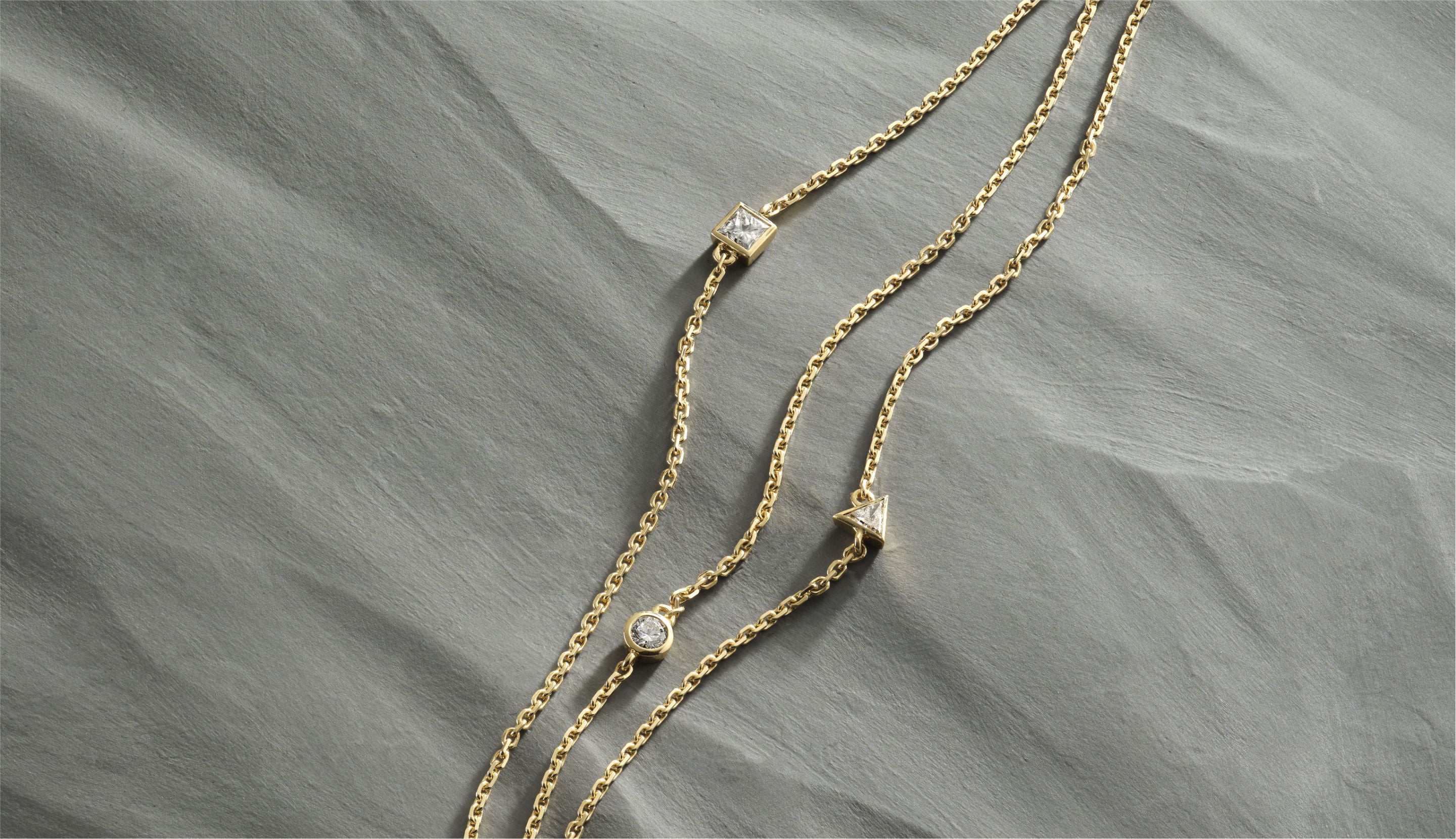 Blonde woman with slicked-back hair wearing a black strapless top and a choker necklace with a large light blue gemstone.