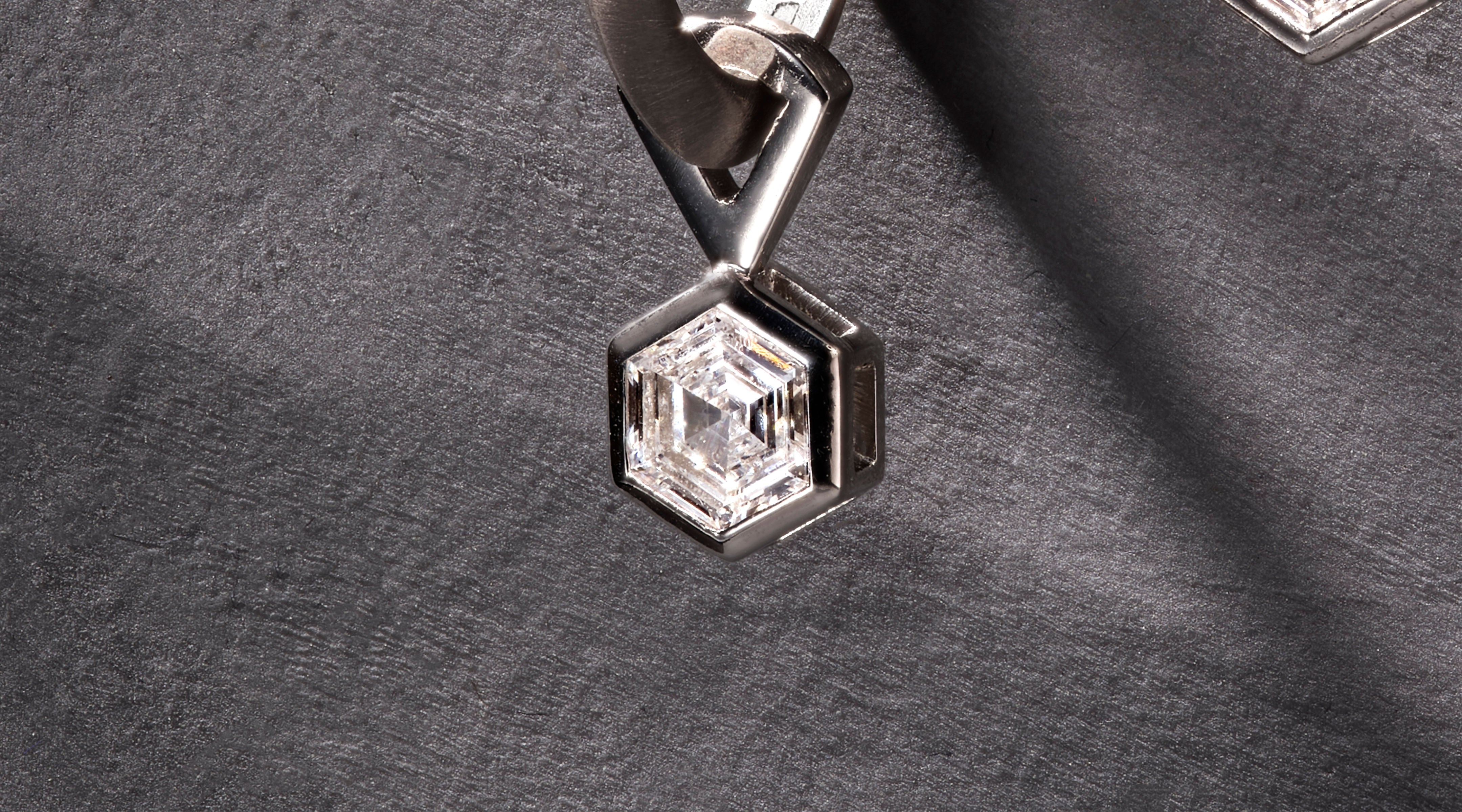 Blonde woman with slicked-back hair wearing a black strapless top and a choker necklace with a large light blue gemstone.