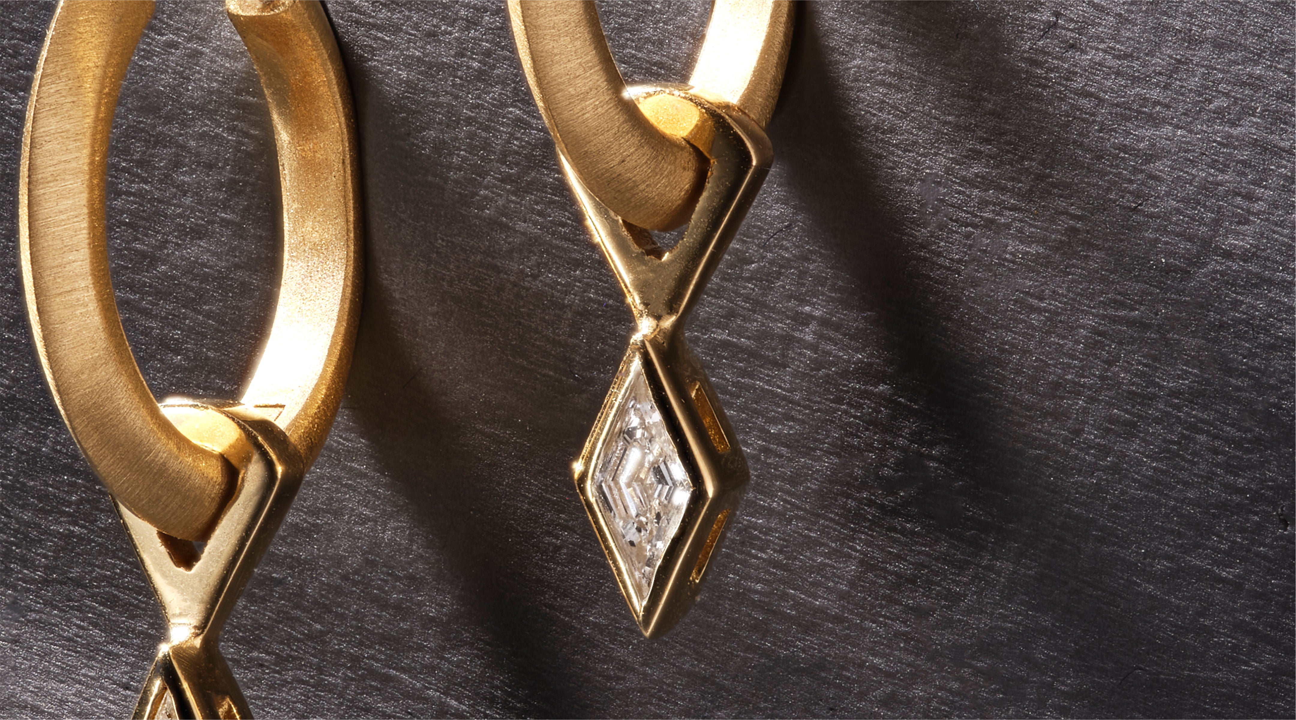 Blonde woman with slicked-back hair wearing a black strapless top and a choker necklace with a large light blue gemstone.