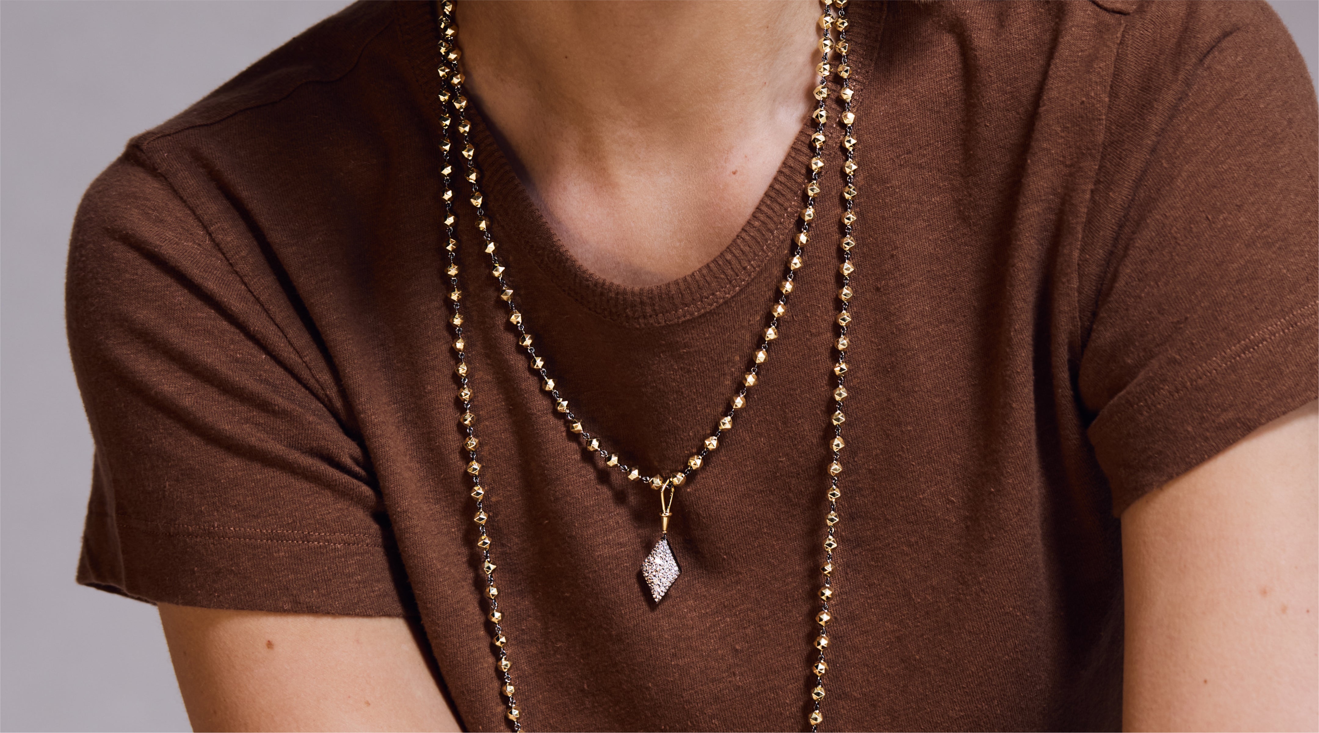 Blonde woman with slicked-back hair wearing a black strapless top and a choker necklace with a large light blue gemstone.