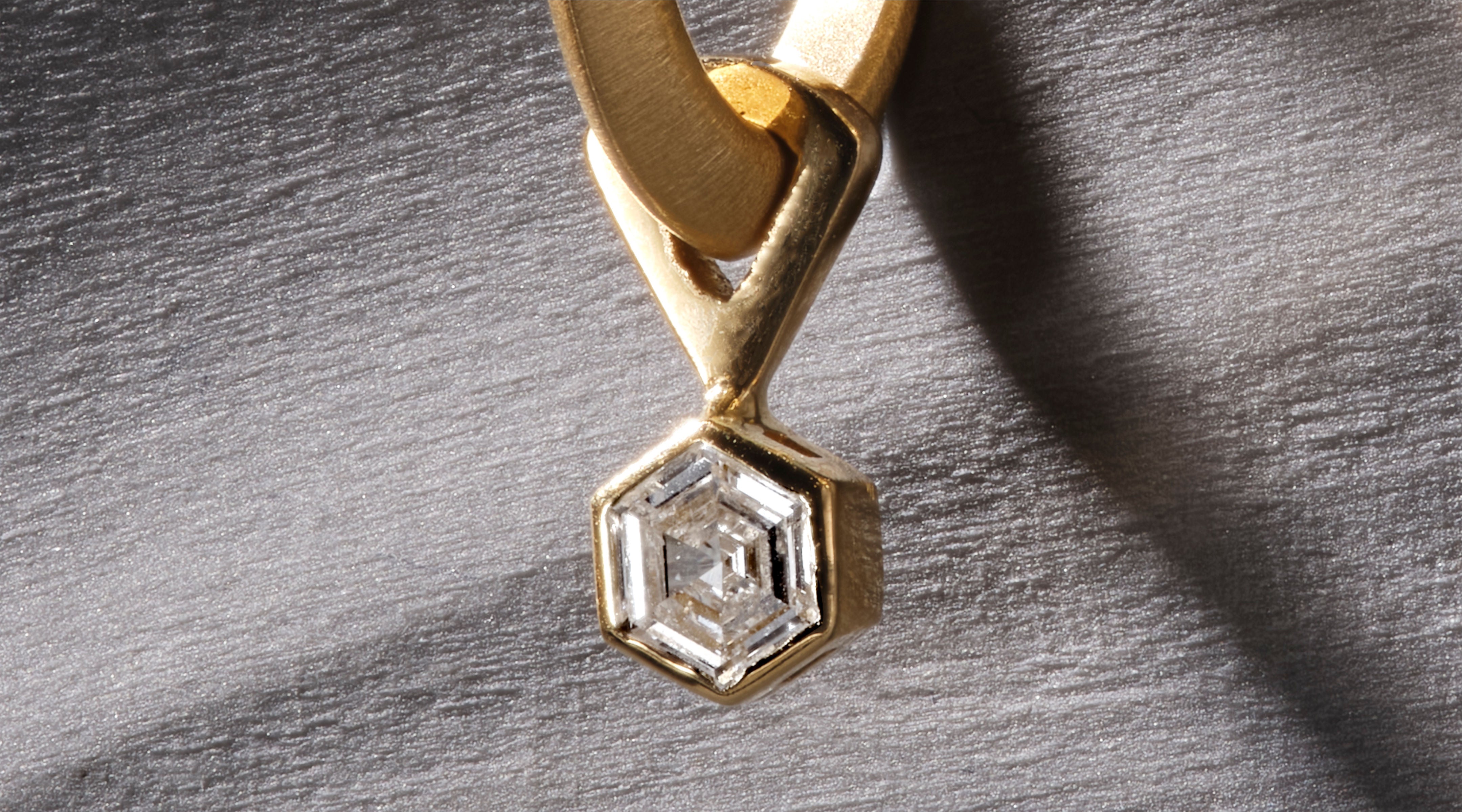 Blonde woman with slicked-back hair wearing a black strapless top and a choker necklace with a large light blue gemstone.