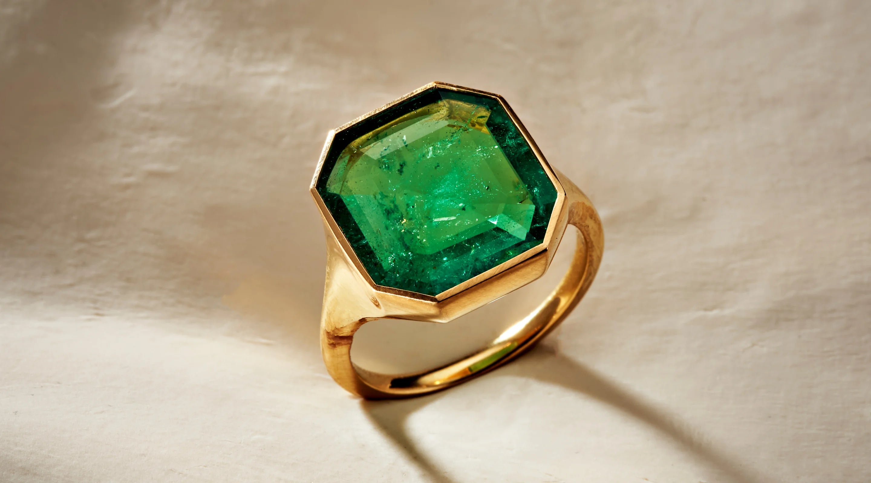 Blonde woman with slicked-back hair wearing a black strapless top and a choker necklace with a large light blue gemstone.