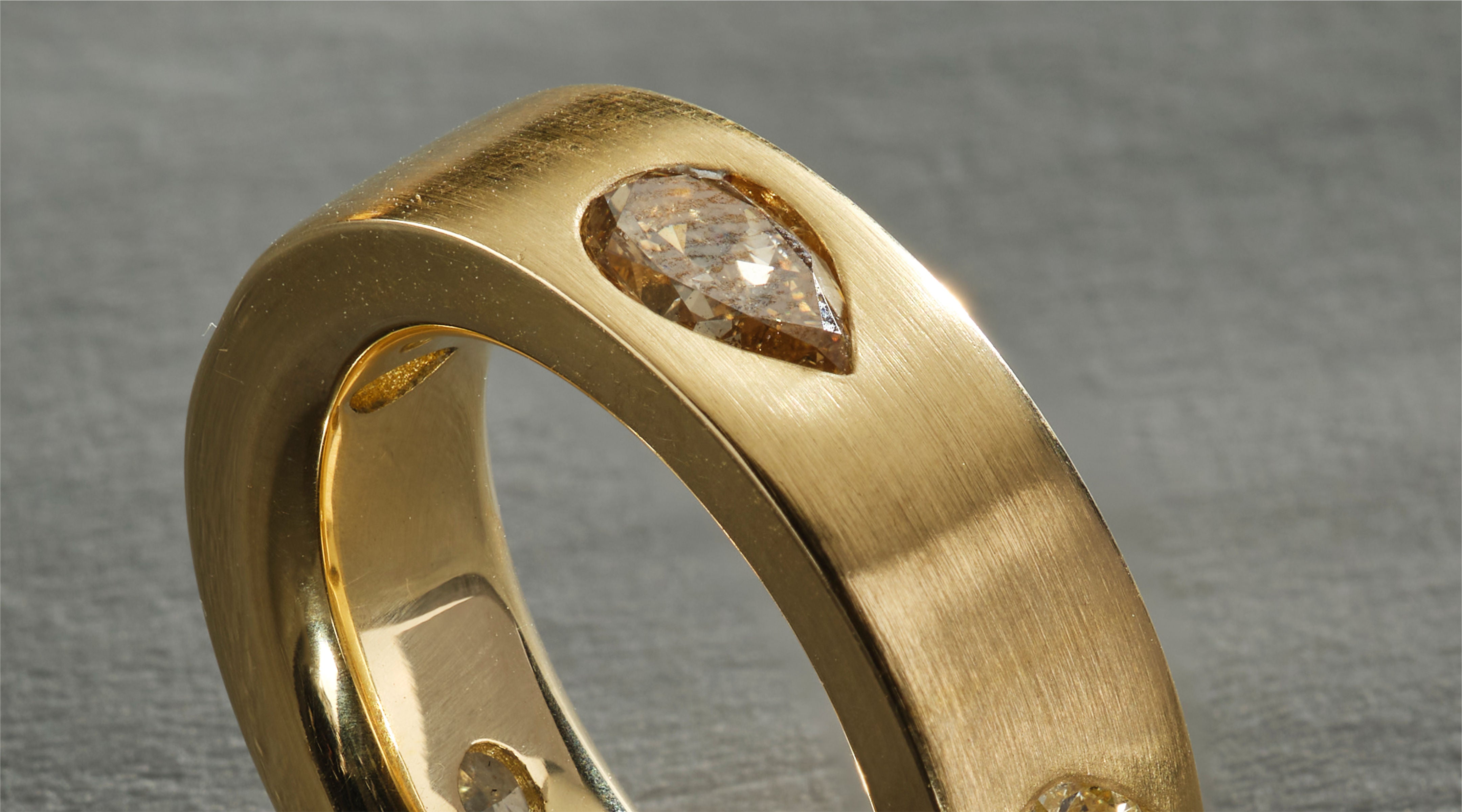 Blonde woman with slicked-back hair wearing a black strapless top and a choker necklace with a large light blue gemstone.