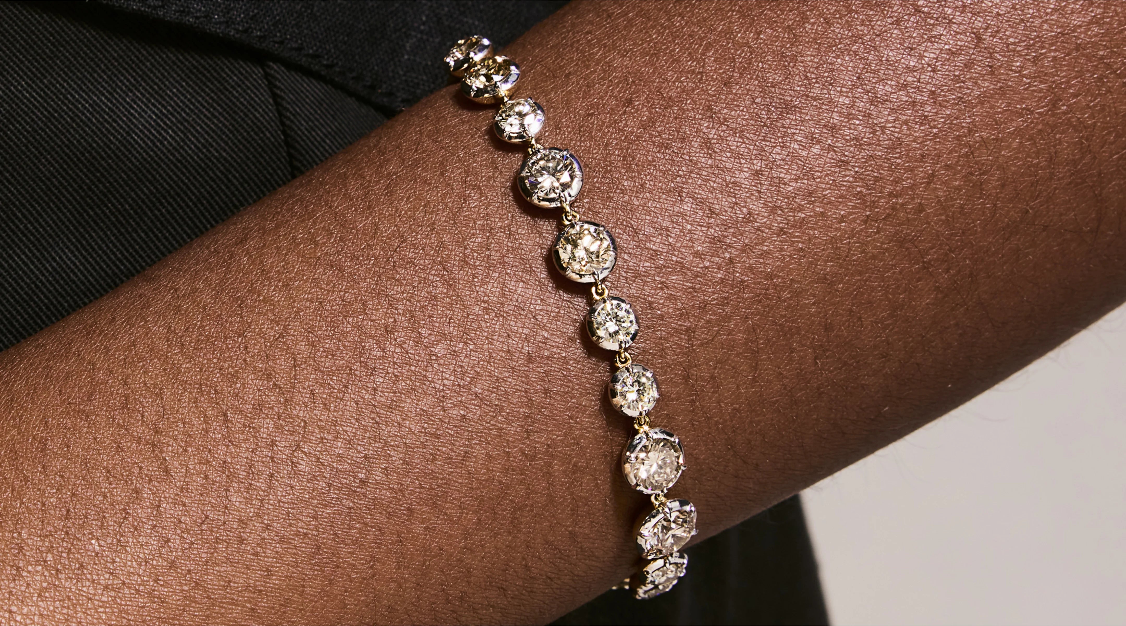Blonde woman with slicked-back hair wearing a black strapless top and a choker necklace with a large light blue gemstone.