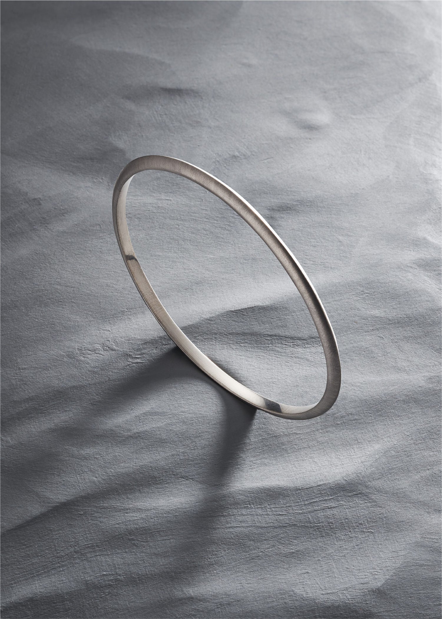 White gold bracelet on a textured gray surface.