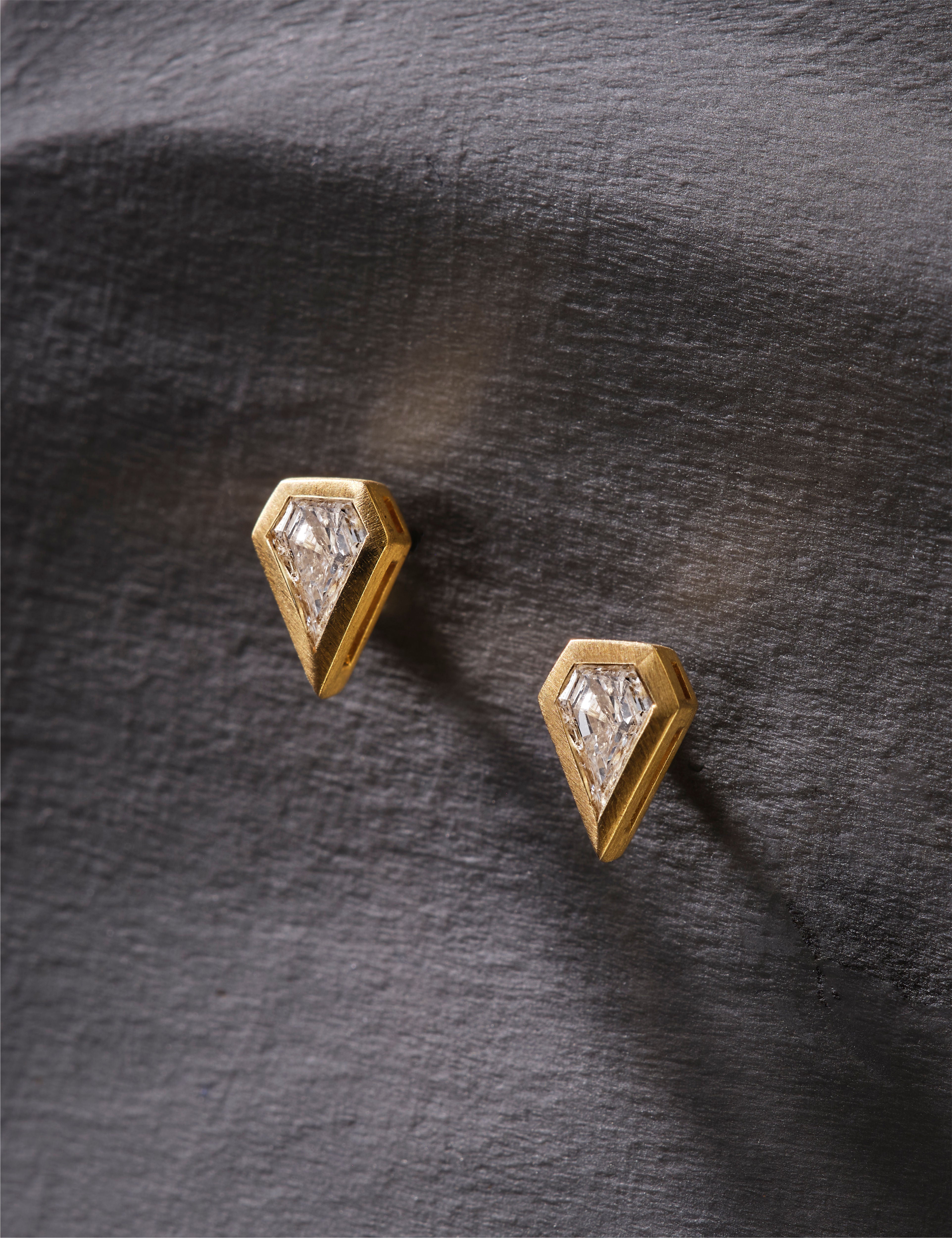 Gold earrings with clear gemstones on a white background.