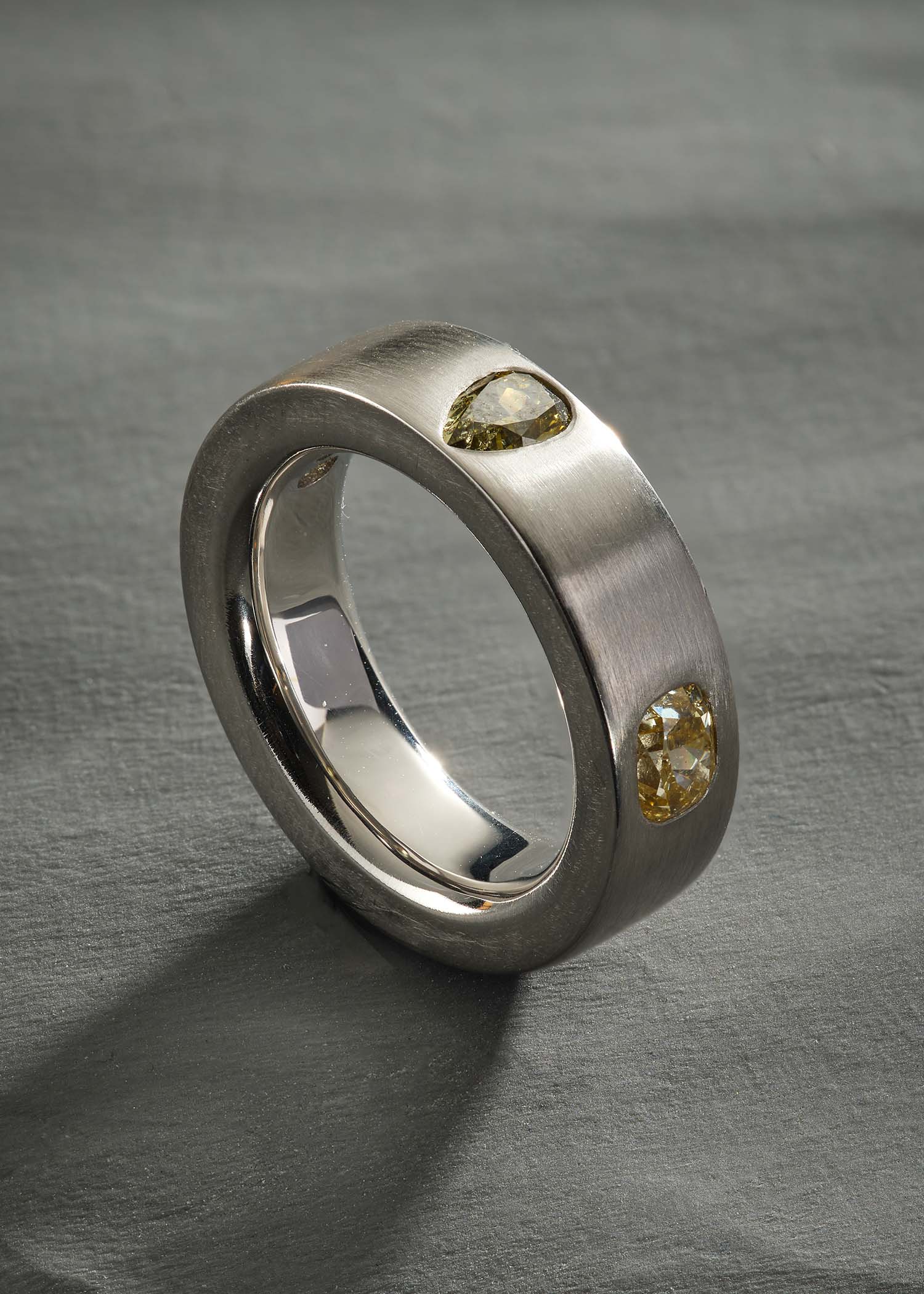 Platinum ring with pear-cut diamonds on matte textured surface.