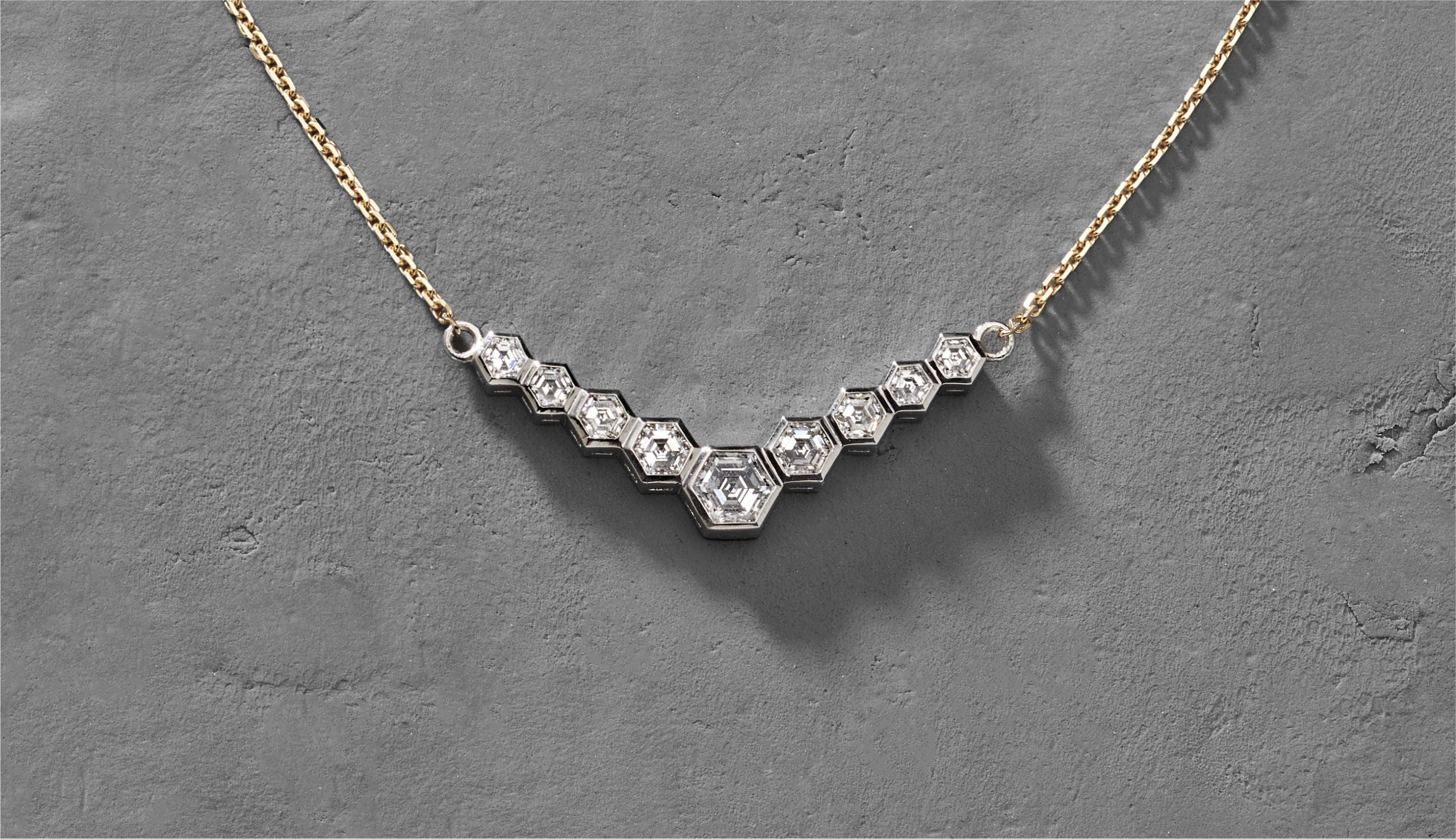 Blonde woman with slicked-back hair wearing a black strapless top and a choker necklace with a large light blue gemstone.