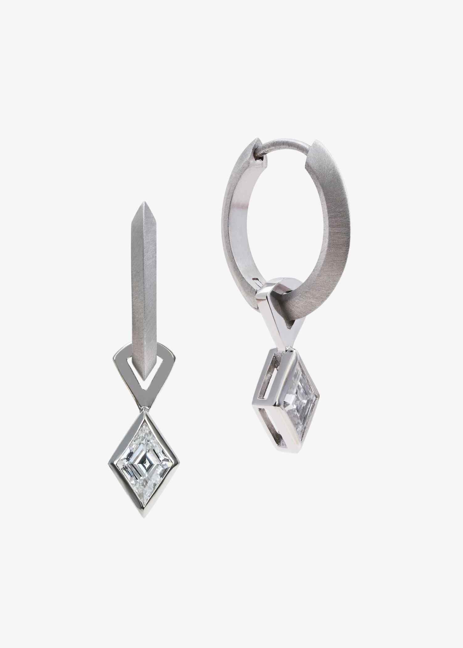 Platinum hoop earrings featuring lozenge-cut diamonds on grey textured surface.