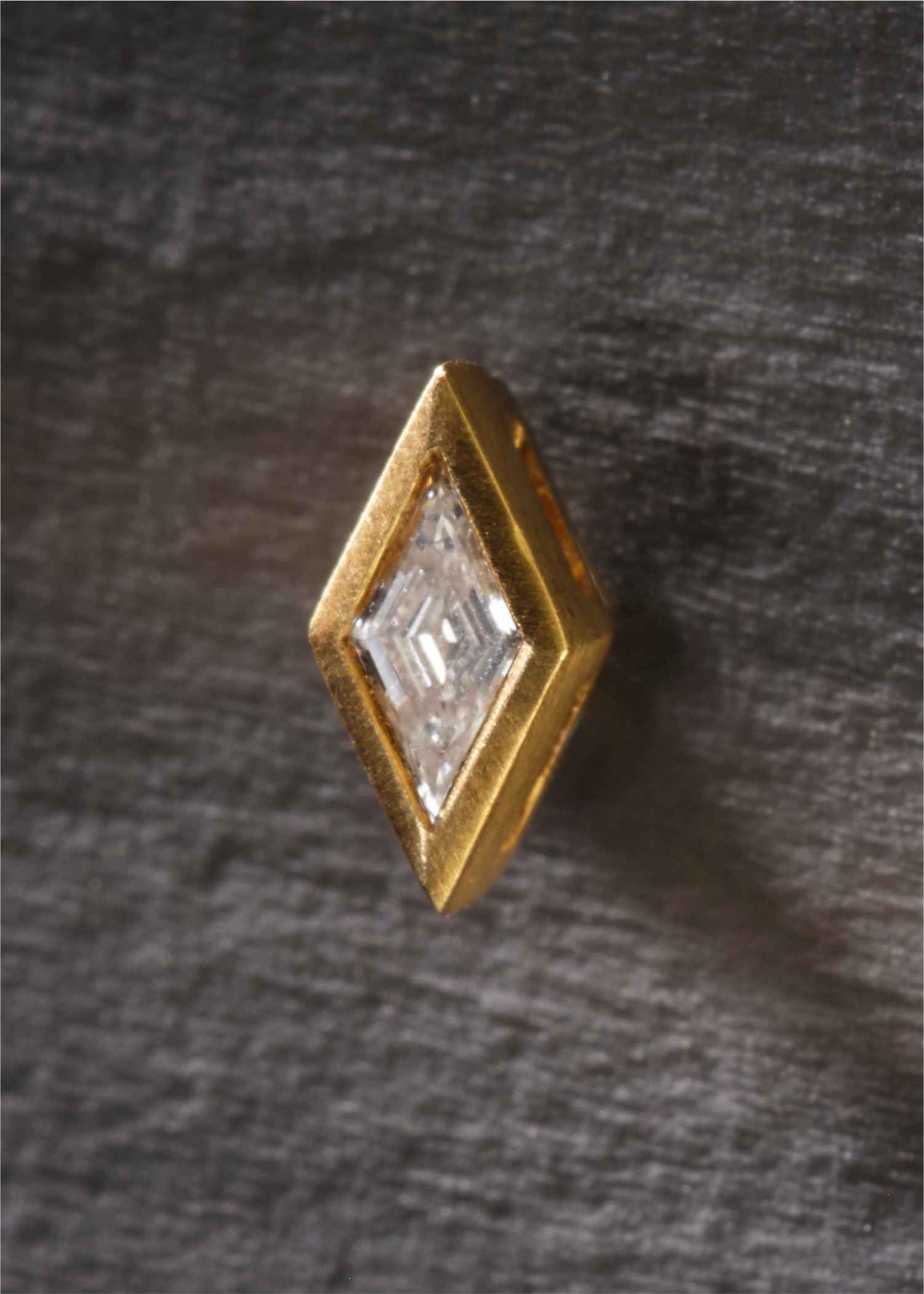 Gold geometric earrings with clear gemstones on a white background.