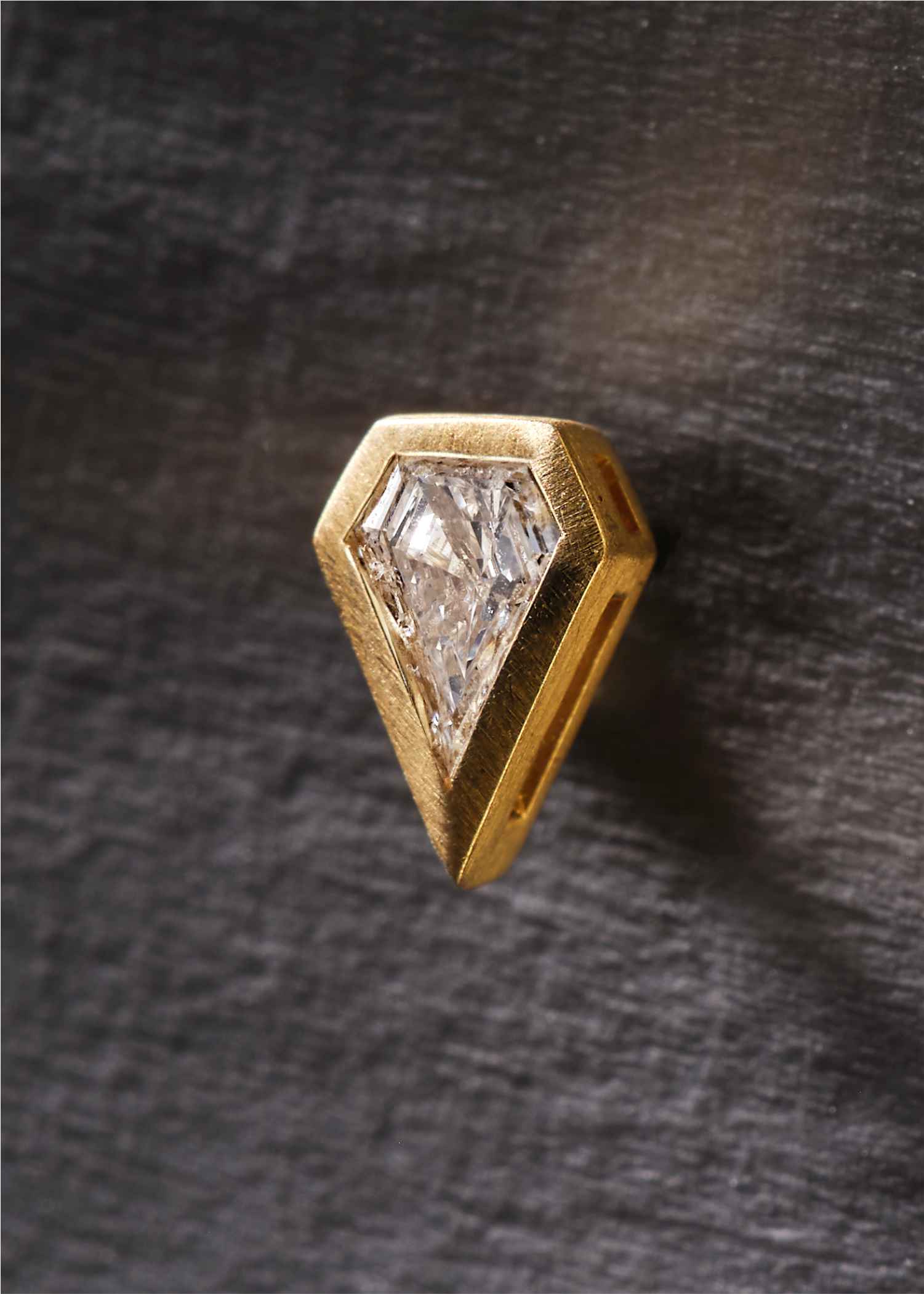 Gold triangle-shaped stud earrings with clear gemstones on a white background.