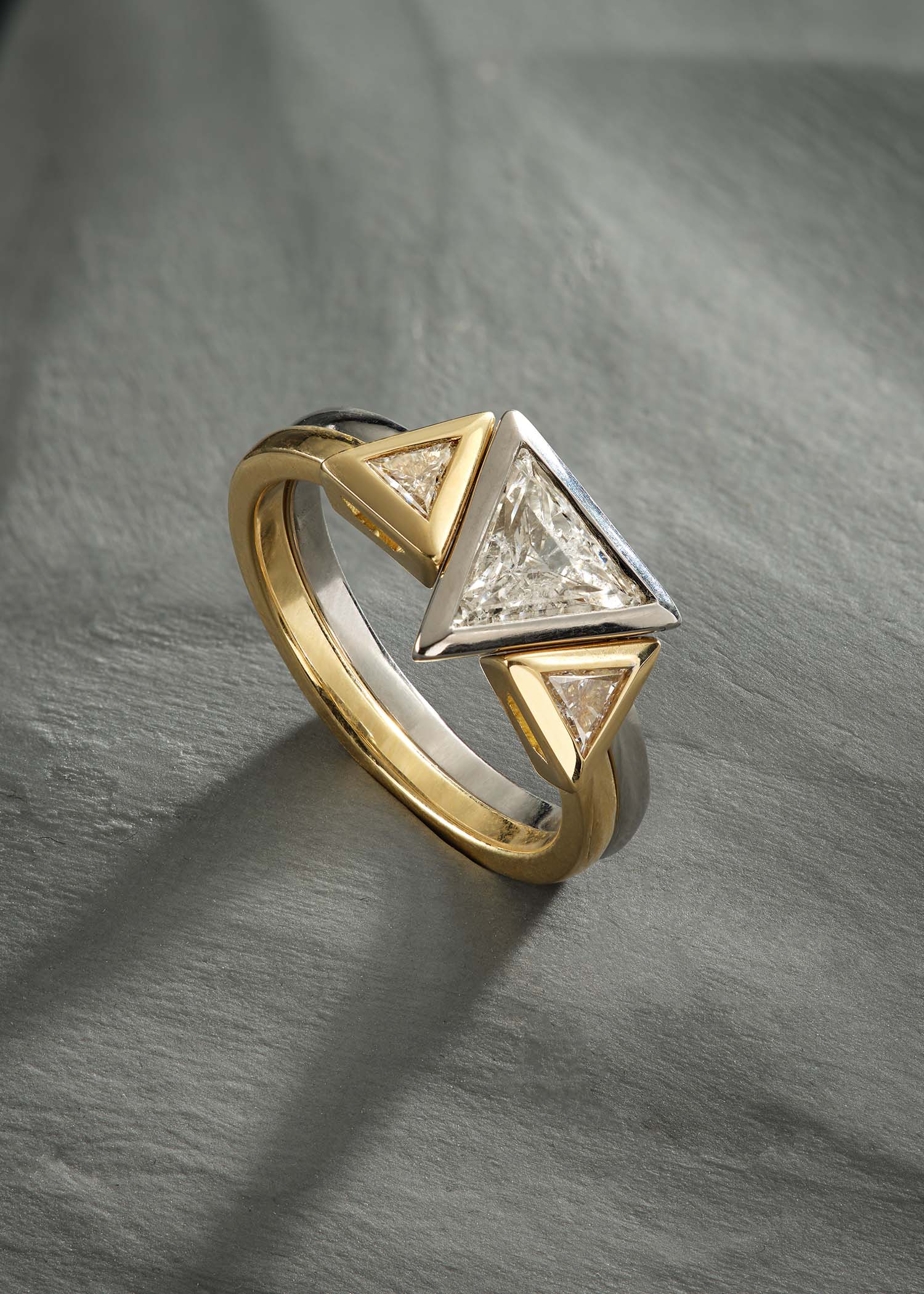 Close-up of yellow gold ring featuring twin triangular diamonds with modern open design.