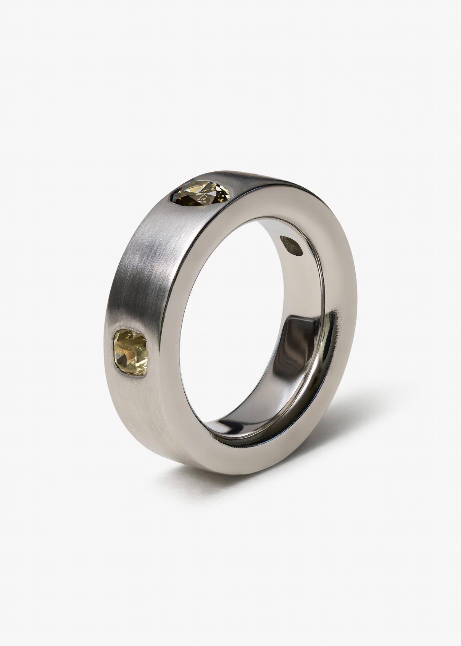 Platinum ring with pear-cut diamonds on matte textured surface.